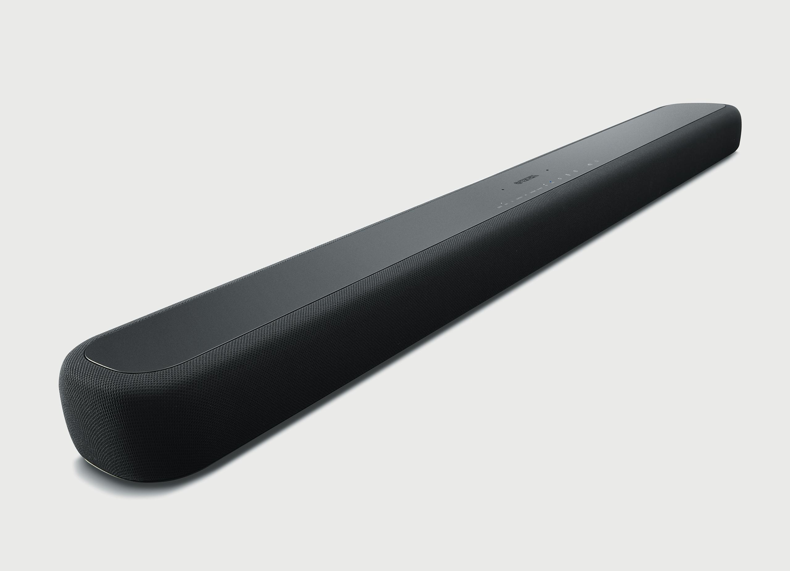 Eine schwarze Soundbar auf weißer Oberfläche, mit abgerundeten Kanten und einem dunklen Stoff, der den Lautsprecher bedeckt.