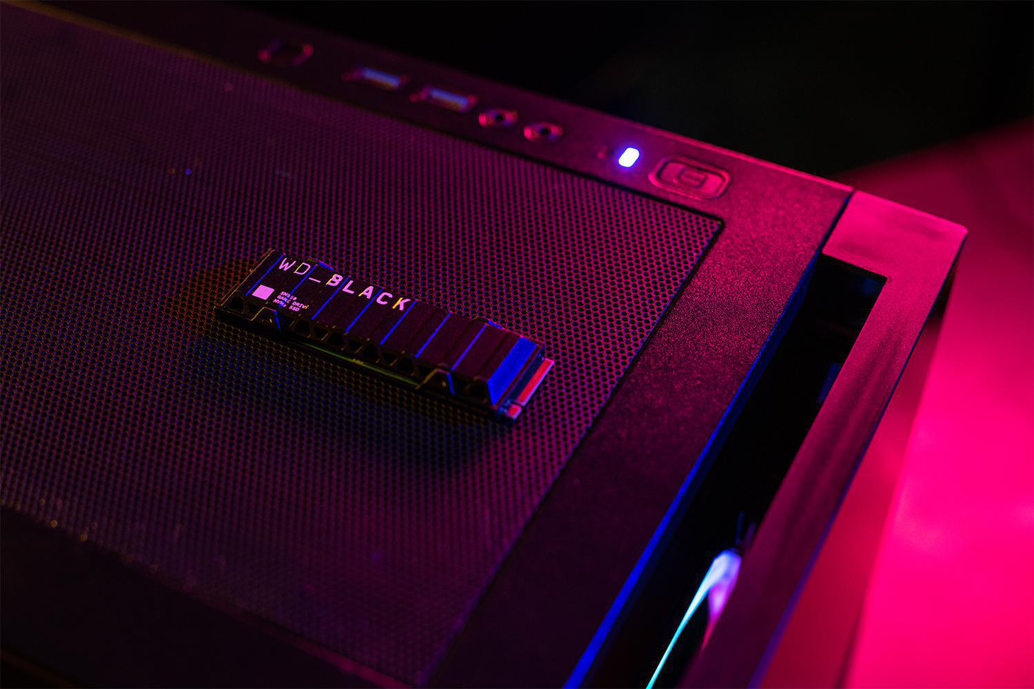 Schwarzes Computergehäuse mit installierter WD_BLACK SSD, beleuchtet mit lila und roten Lichtern.