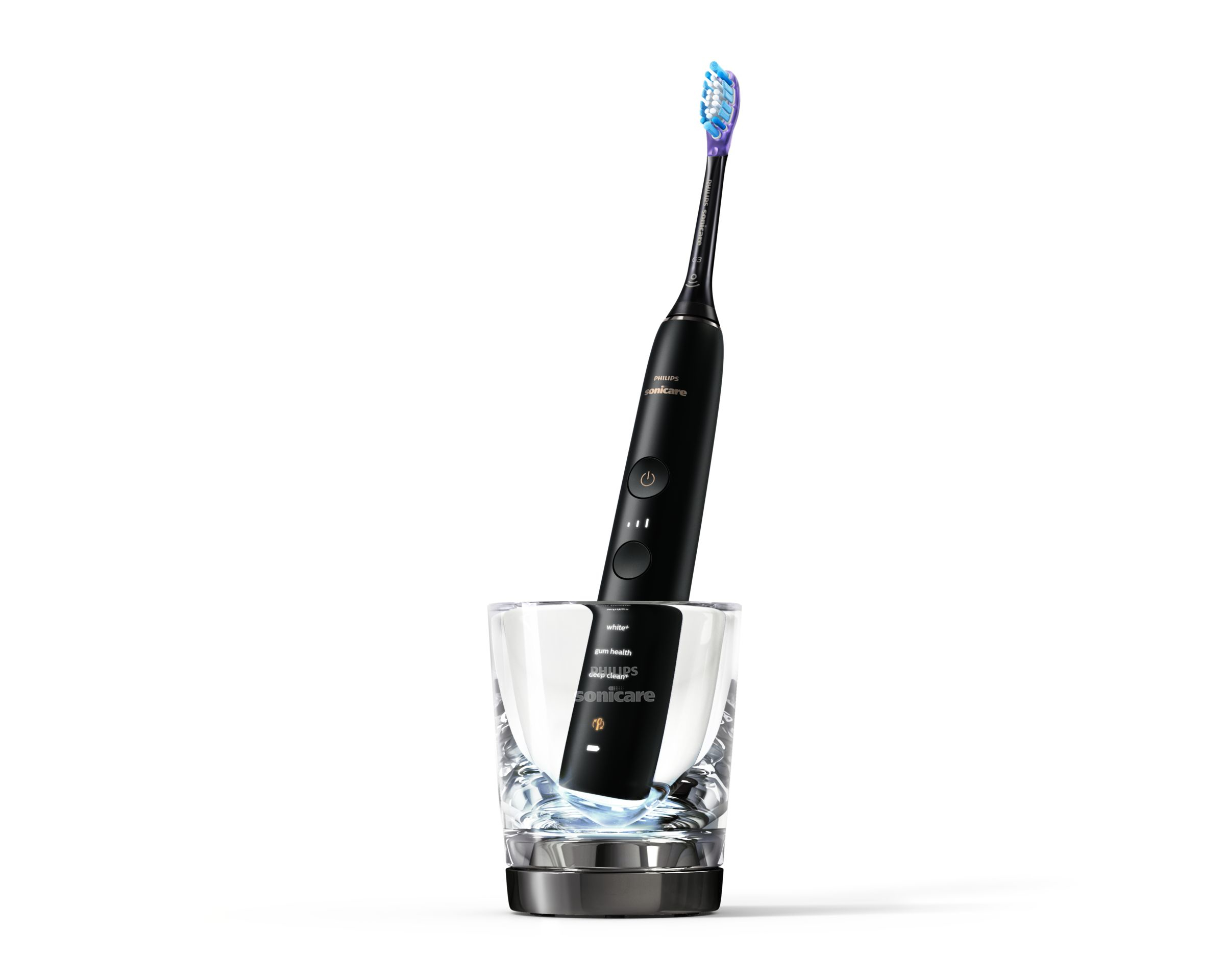 Brosse à dents électrique noire dans un verre, sur fond blanc.