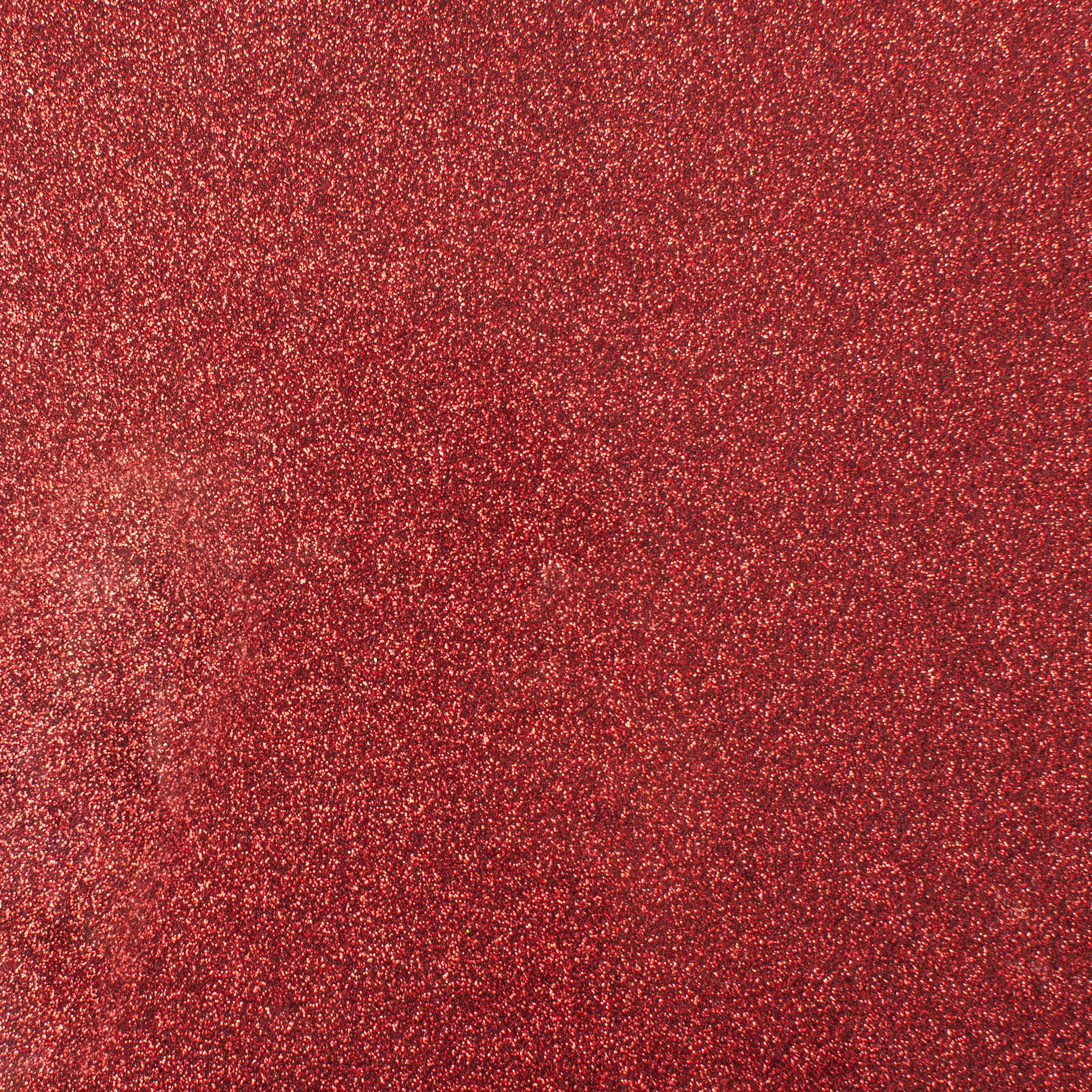 Nahaufnahme einer roten Glitzeroberfläche. Die Textur ist dicht mit winzigen, reflektierenden Partikeln.