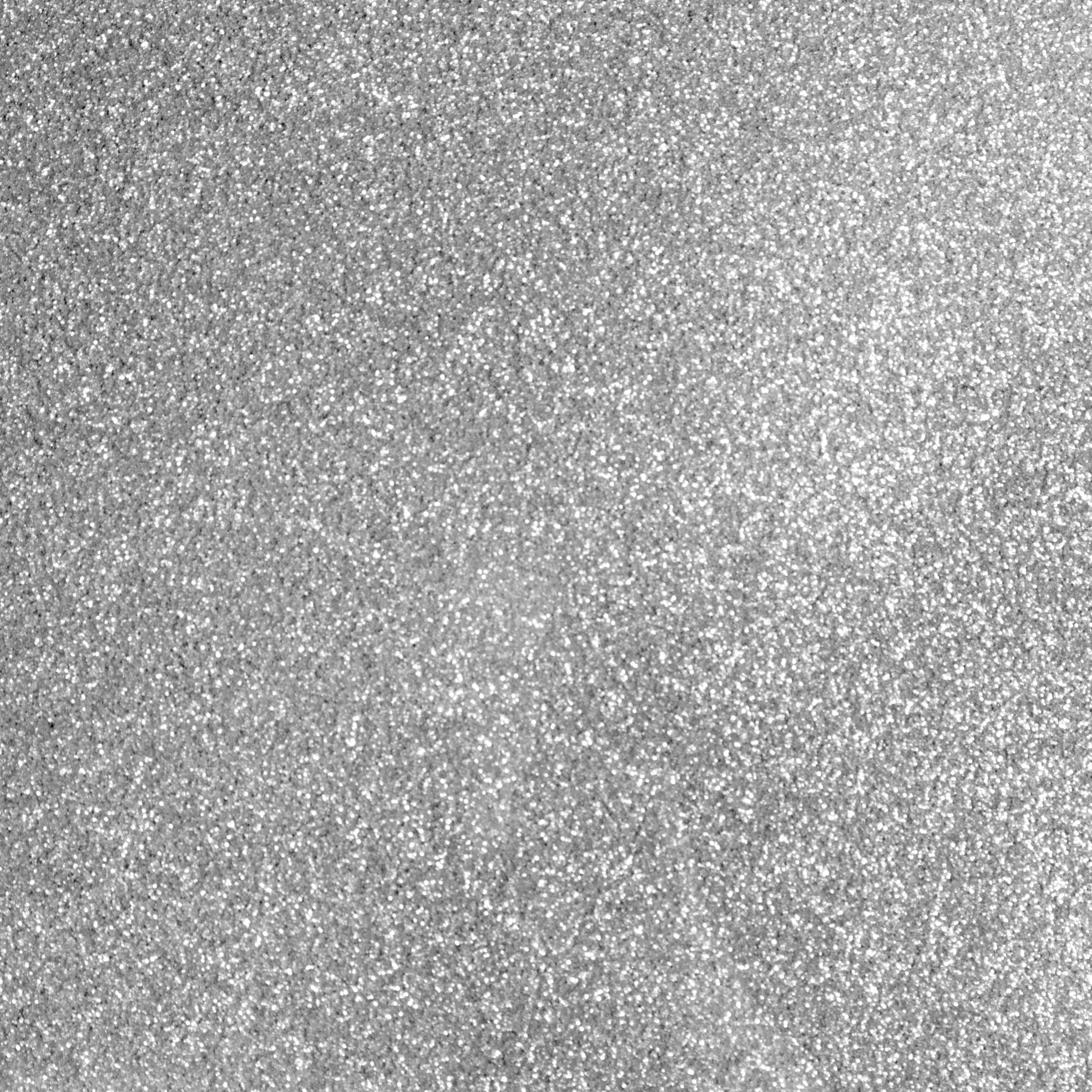Nahaufnahme einer glitzernden, strukturierten Oberfläche. Sie ist mit winzigen, reflektierenden Partikeln bedeckt.