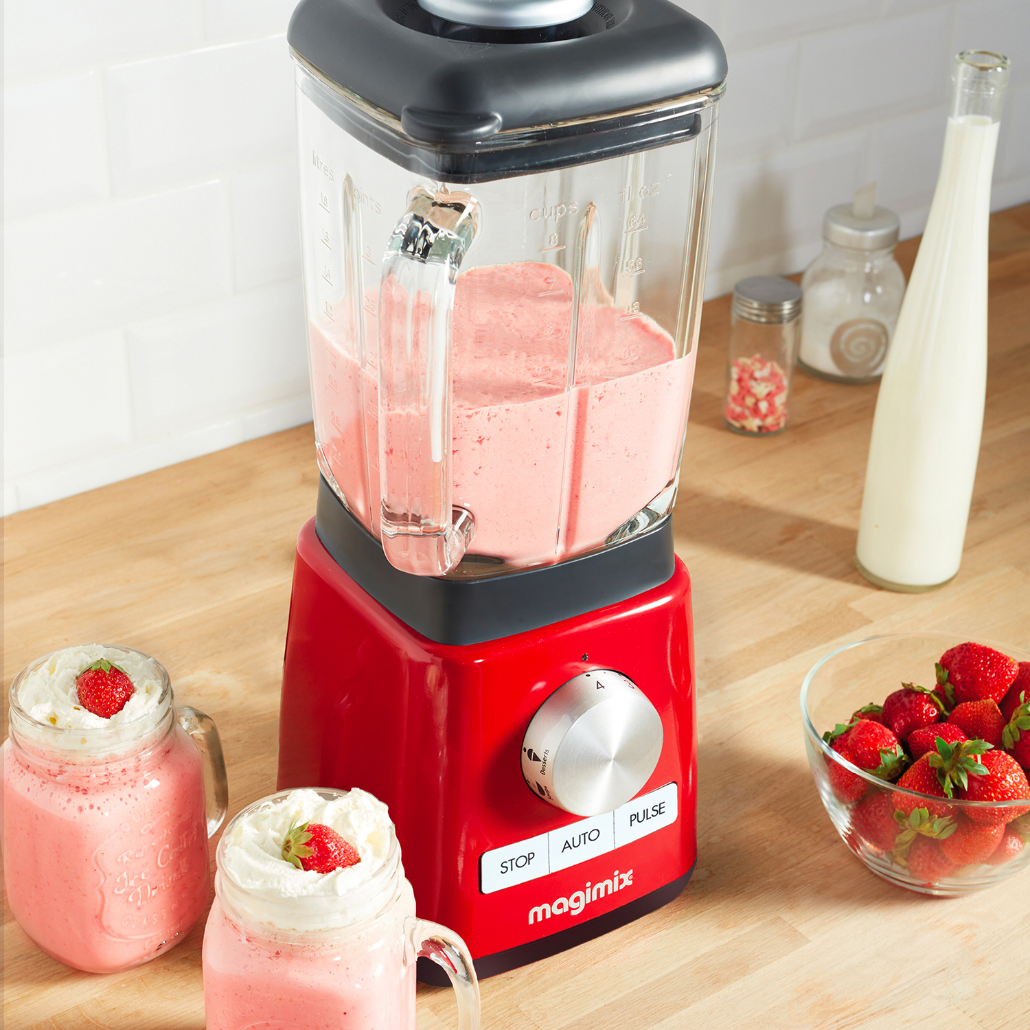Rode blender met een glazen pot gevuld met roze smoothie. Twee smoothies in potten worden ook getoond.