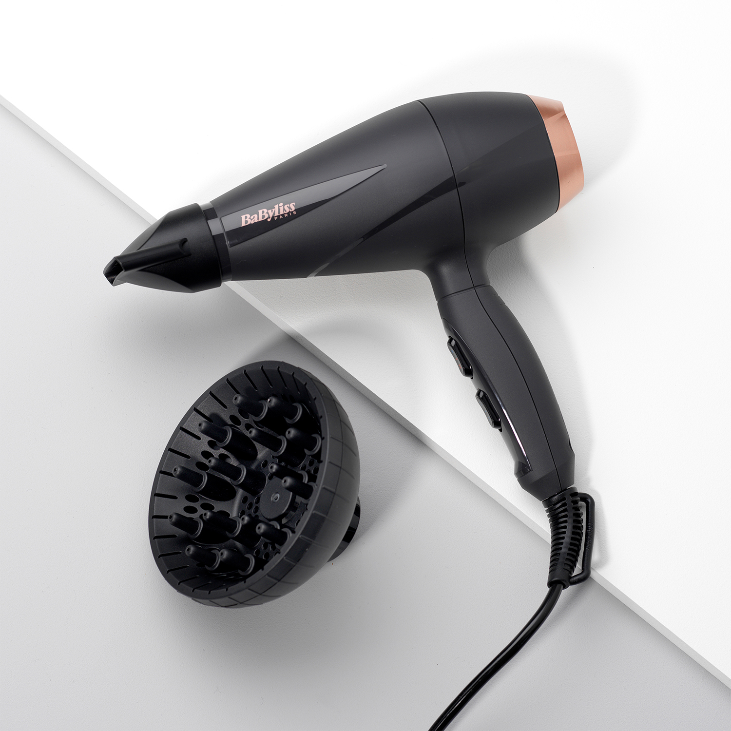 Asciugacapelli nero con diffusore nero. Accenti oro rosa. Sfondo bianco.