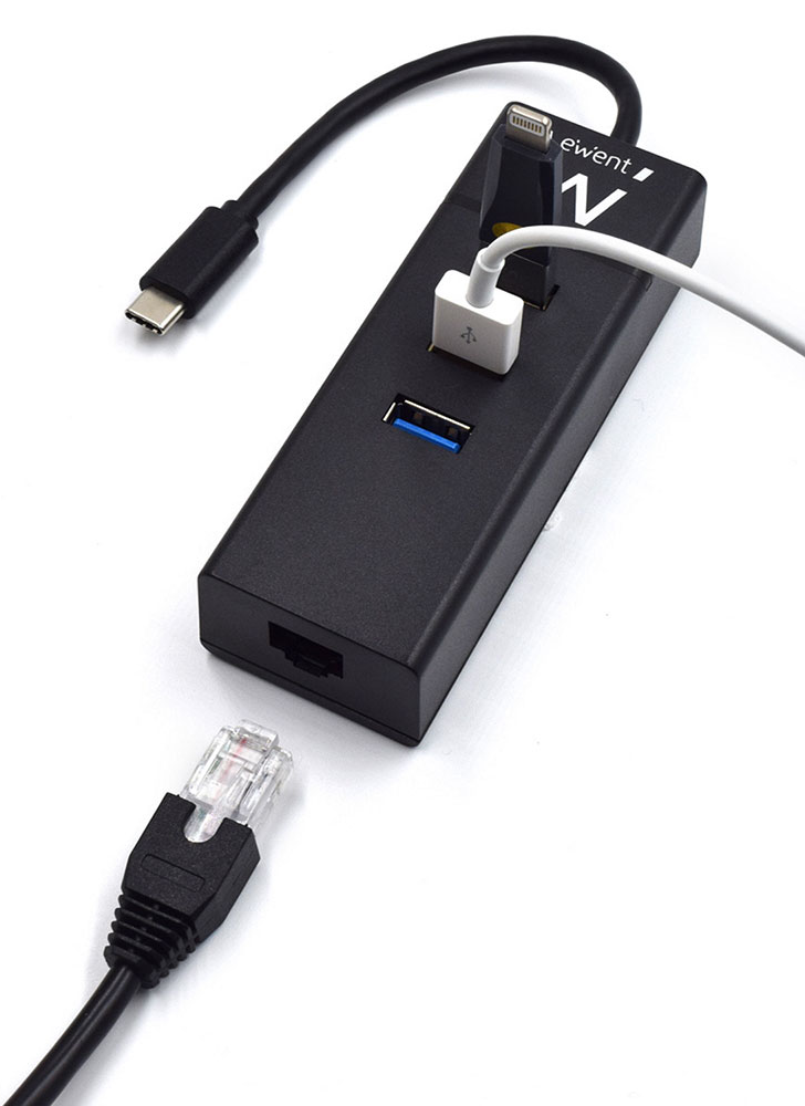 Fekete USB hub Ethernettel és több USB porttal. Különféle kábelek vannak bedugva.