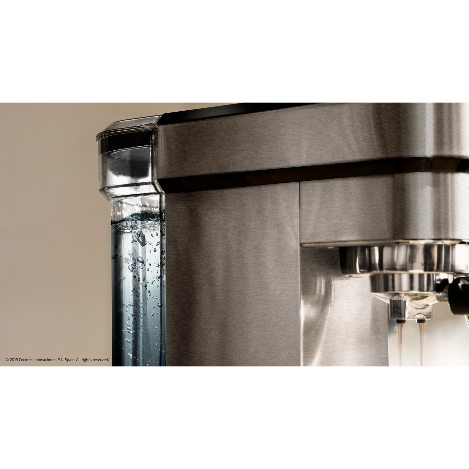 Primer plano de una cafetera de acero inoxidable con agua en un depósito transparente.