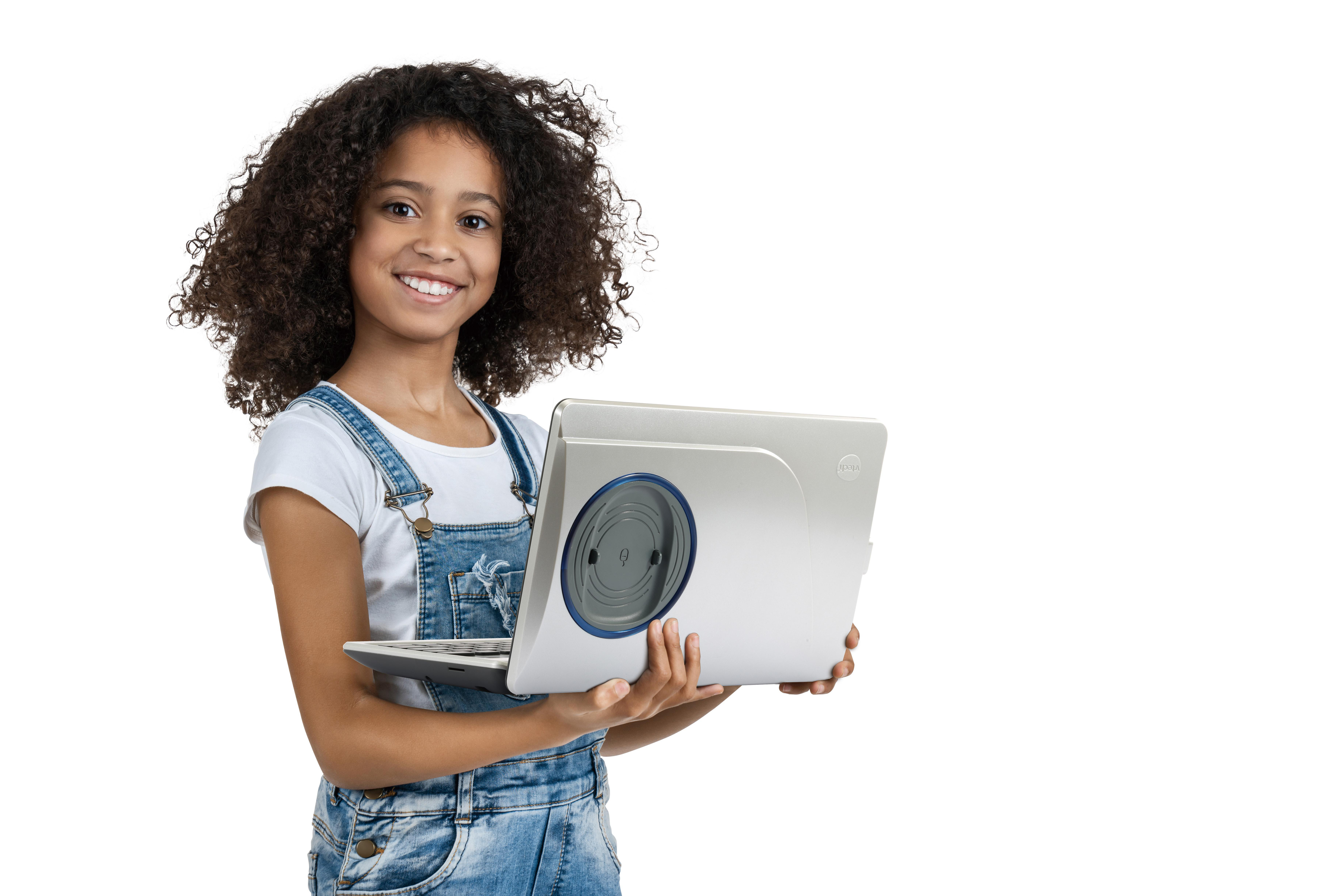 Mädchen hält Laptop, lächelt. Sie trägt weißes Shirt, Jeanslatzhose. Weißer Hintergrund.