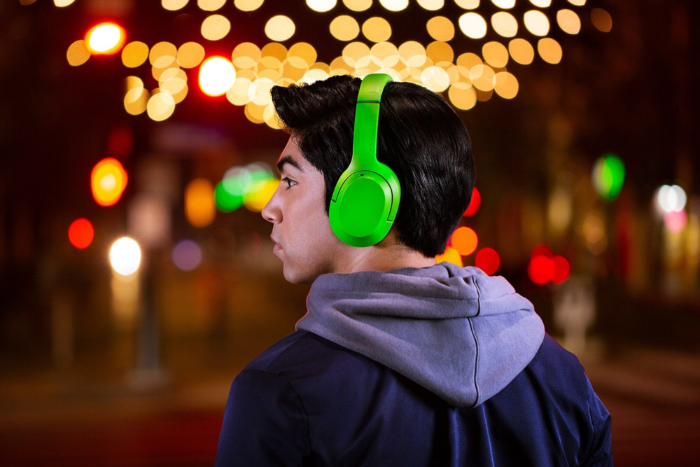 Un homme portant un casque vert et un sweat à capuche bleu, regardant ailleurs la nuit.