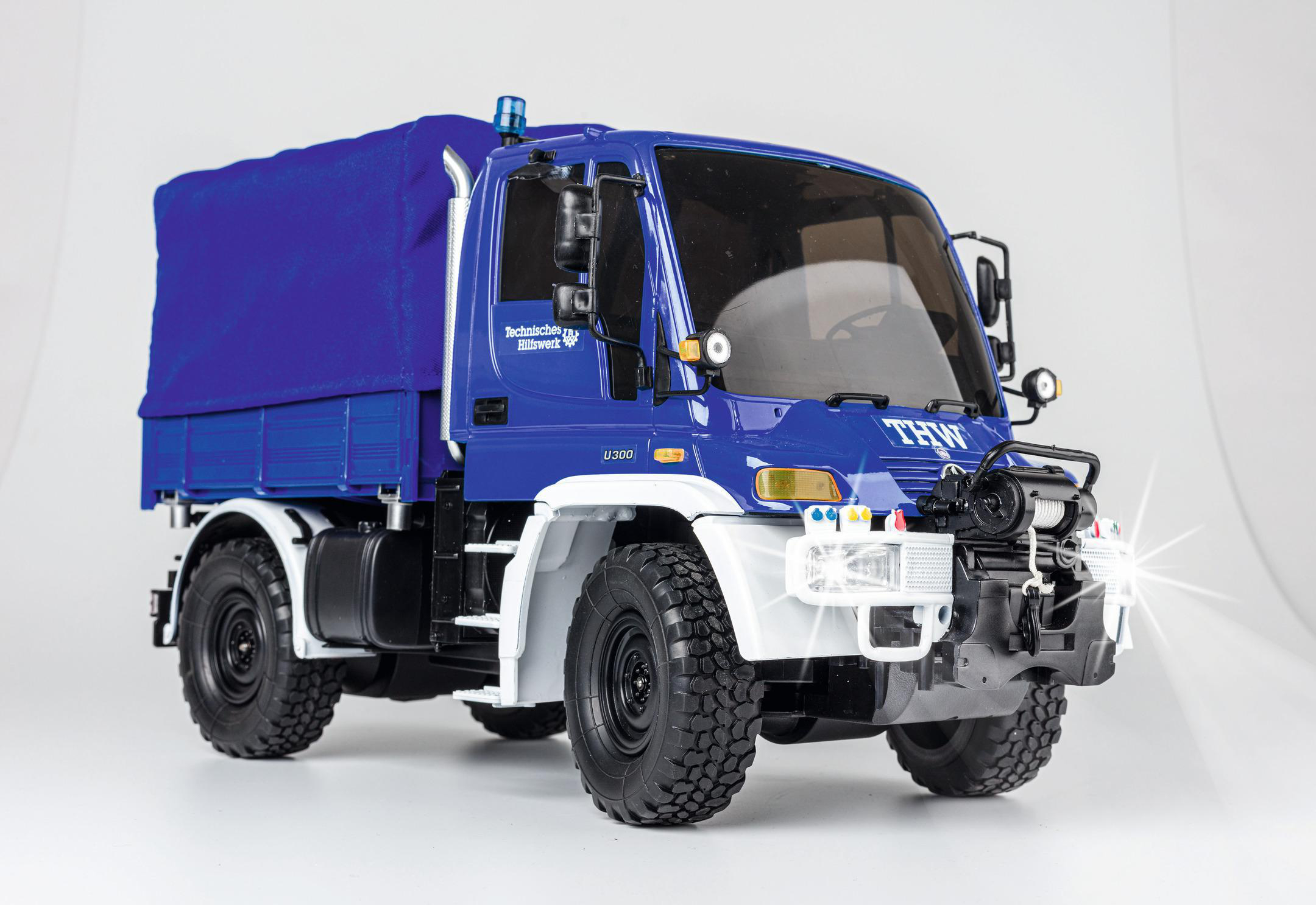 Blau-weißes THW Unimog-Truck-Modell mit blauem Planenaufbau und schwarzen Rädern.