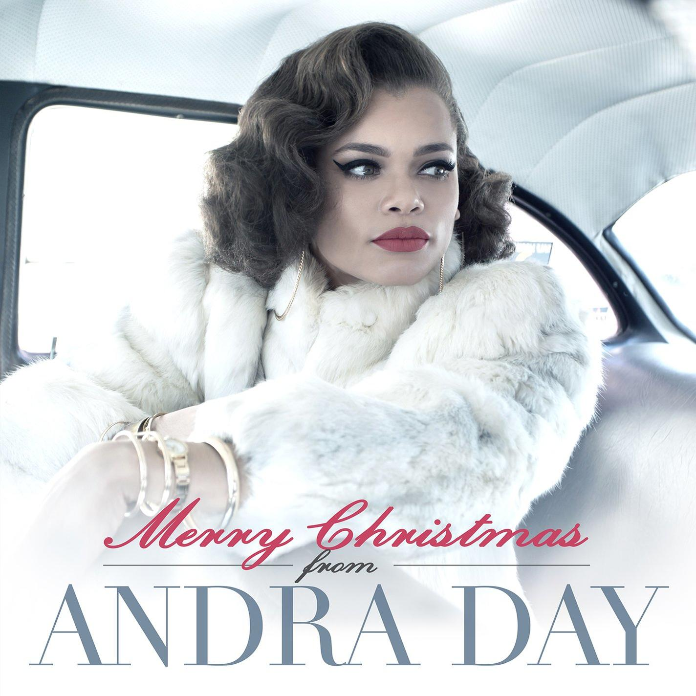 Andra Day egy autóban, fehér szőrmekabátban, piros rúzzsal. Szöveg: Boldog karácsonyt Andra Day-től.