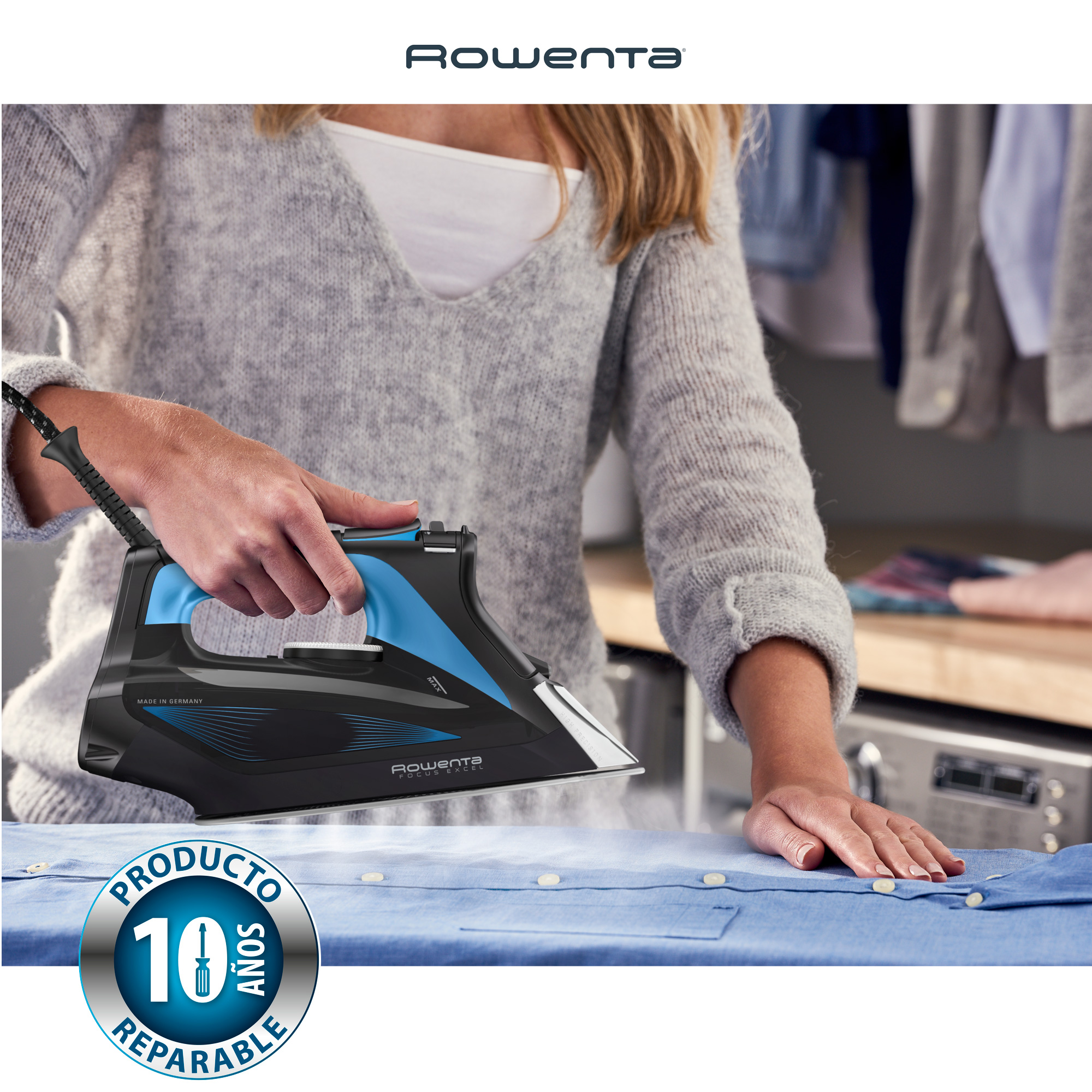 Una mujer planchando una camisa azul con una plancha Rowenta negra y azul, sale vapor.