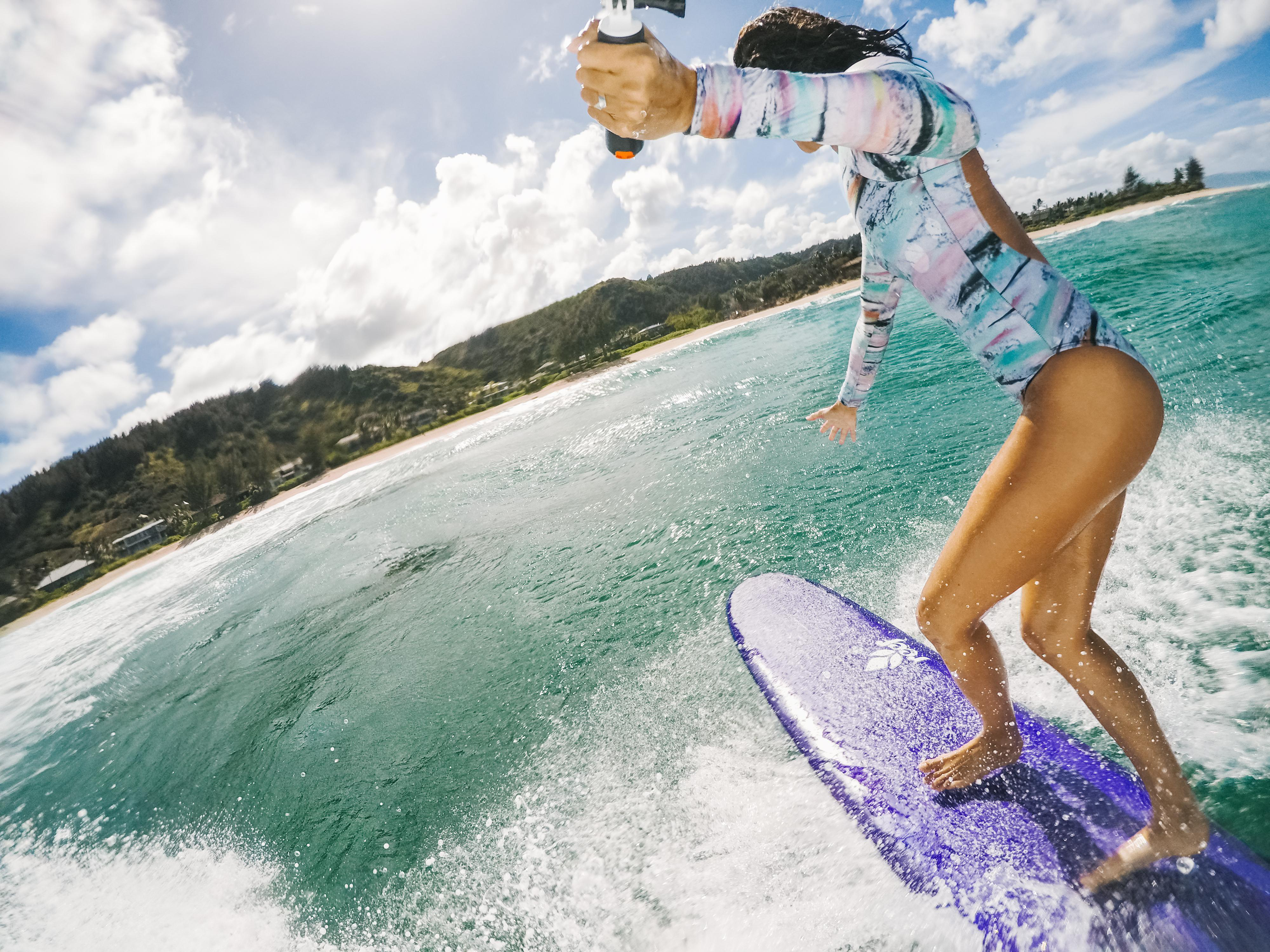 Frau surft auf einem blauen Surfbrett im Meer, sonniger Tag, blauer Himmel.