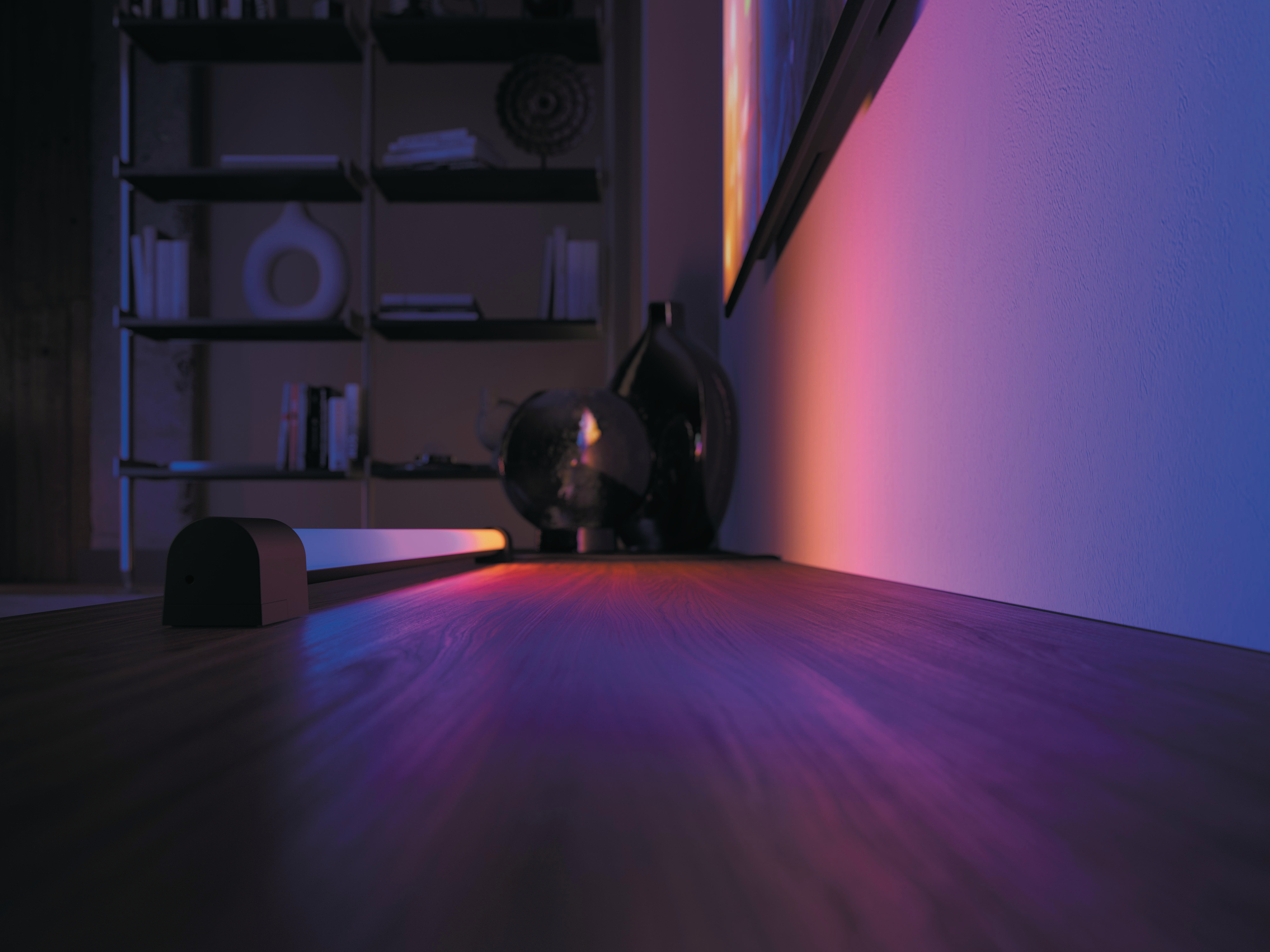 Ein Raum mit einer Lichtleiste auf einer Holzoberfläche und einem Fernseher an der Wand.