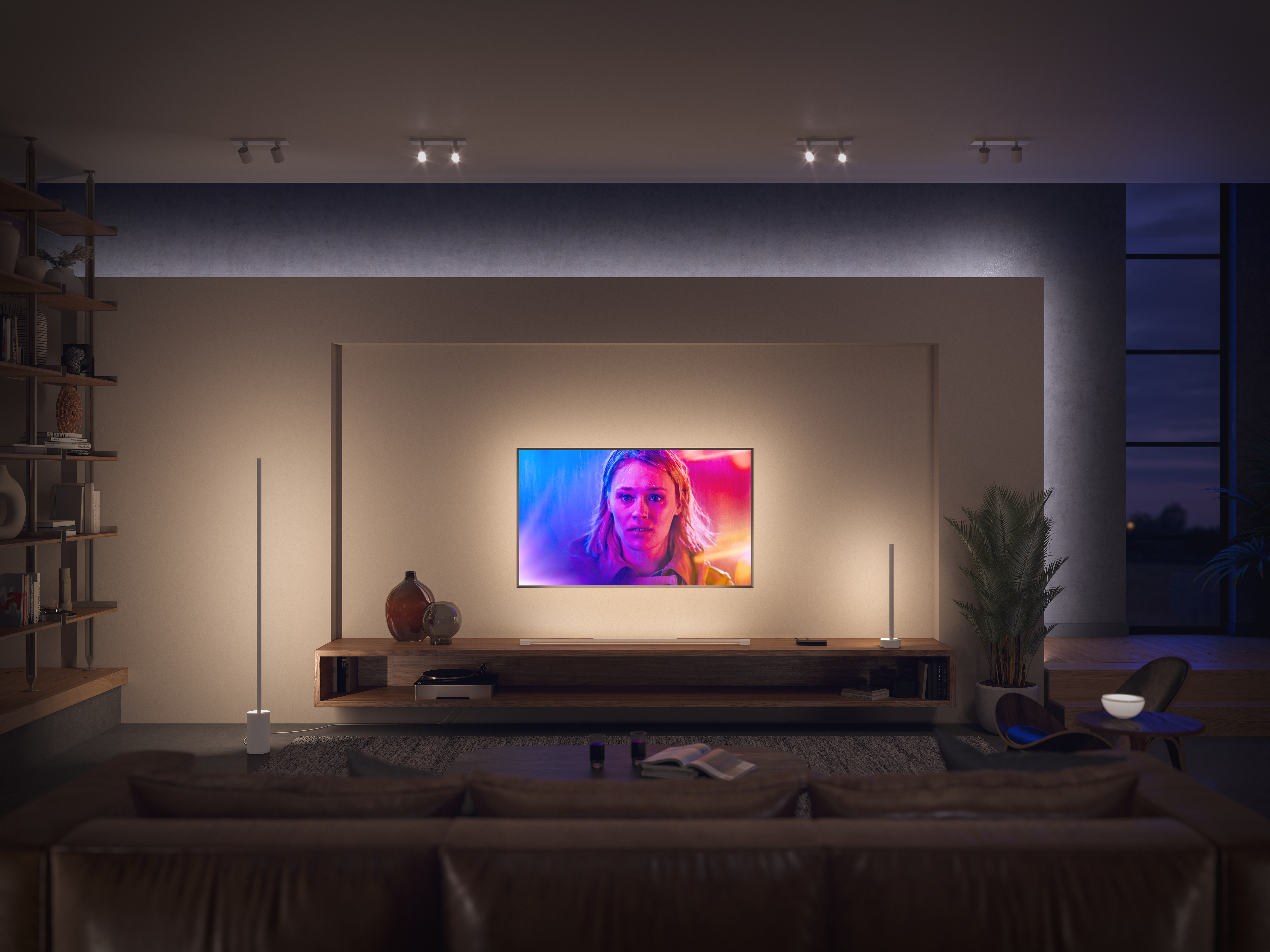 Ein modernes Wohnzimmer. Ein Fernseher ist an der Wand montiert. Zwei Stehlampen und ein braunes Ledersofa sind vorhanden.