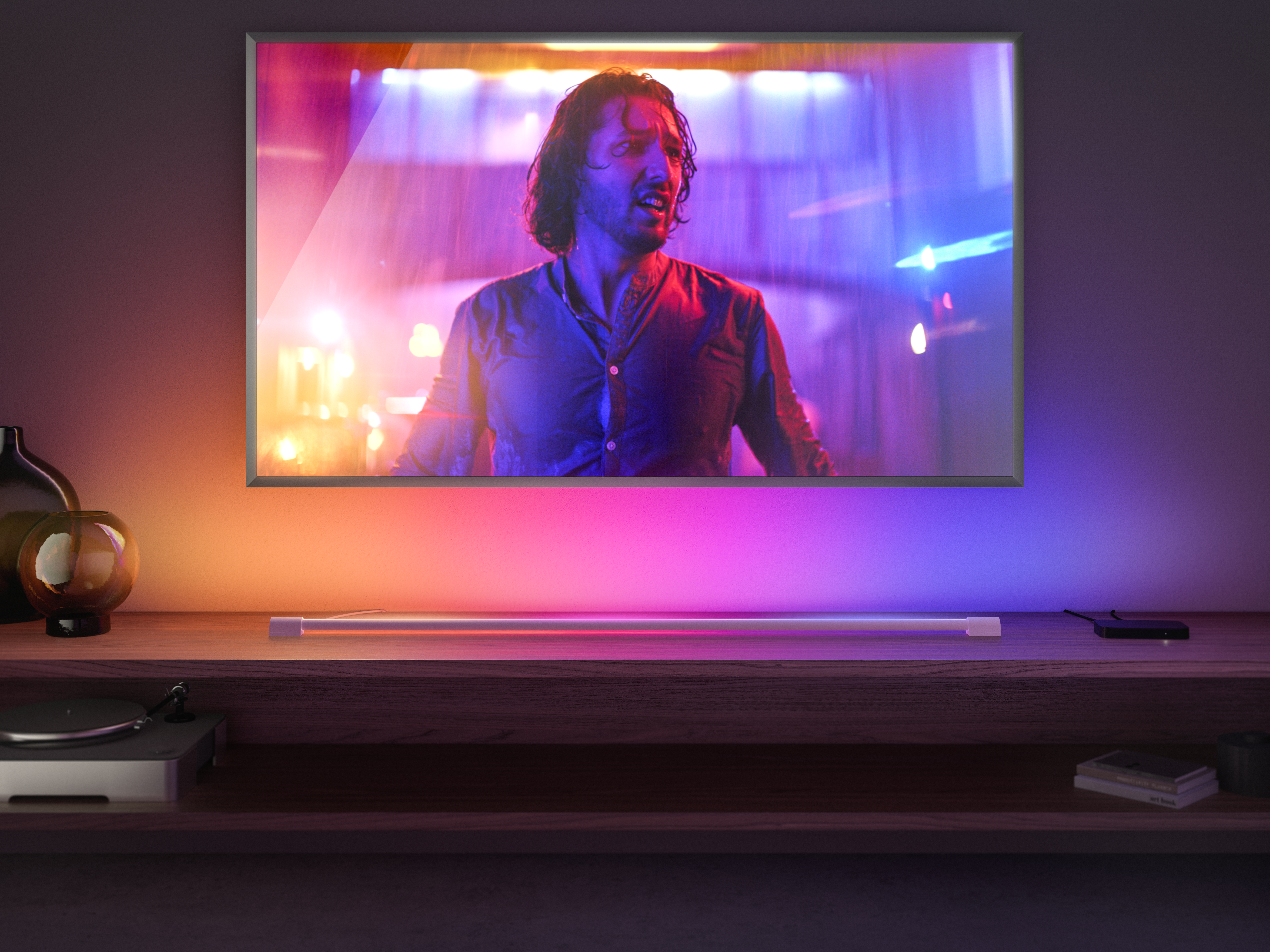 Mann auf dem Fernsehbildschirm. TV steht auf Holztisch. Lampe und andere Gegenstände auf dem Tisch.