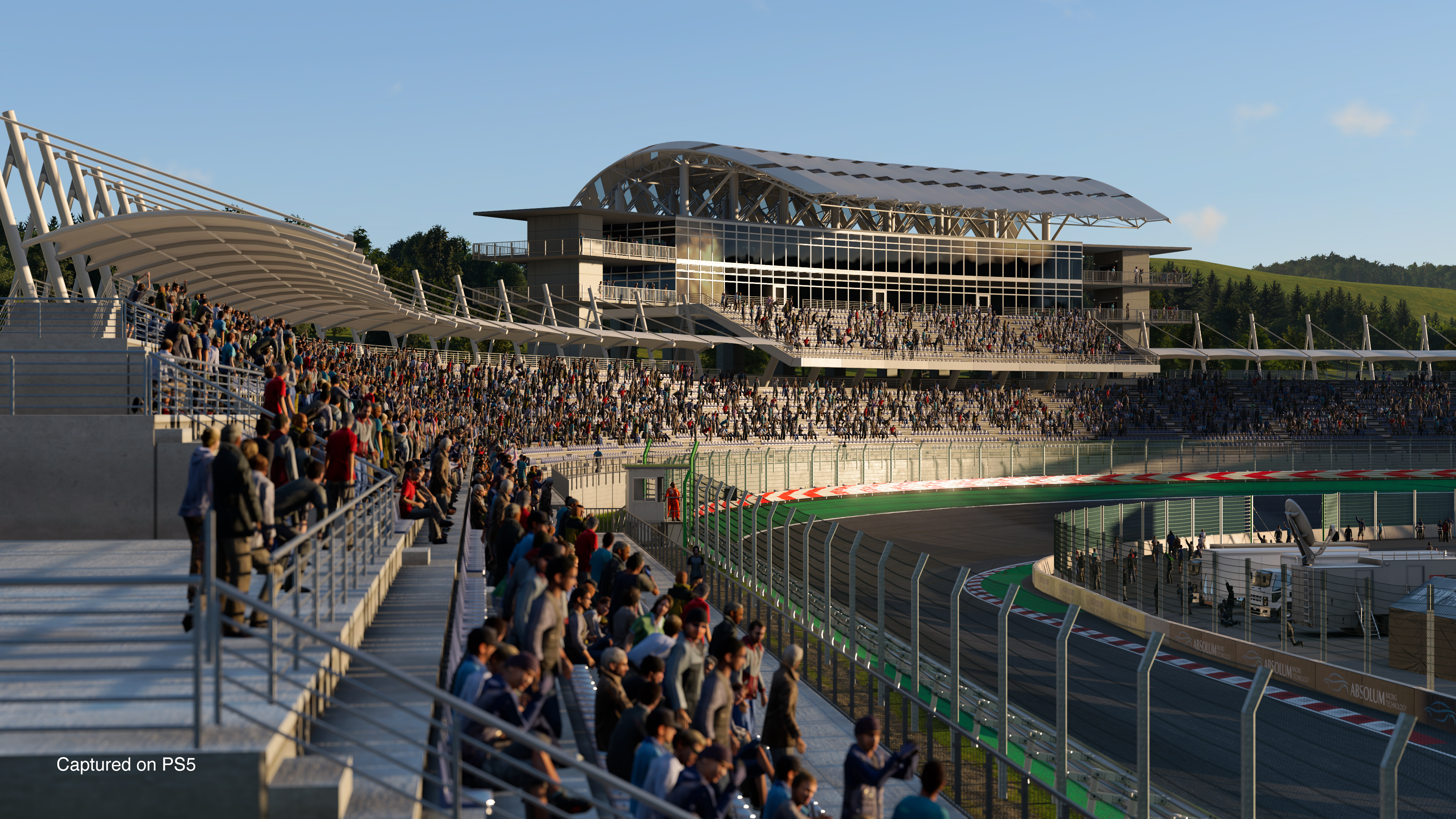 Circuit de course avec spectateurs dans les tribunes et voitures sur la piste. Ciel nuageux.
