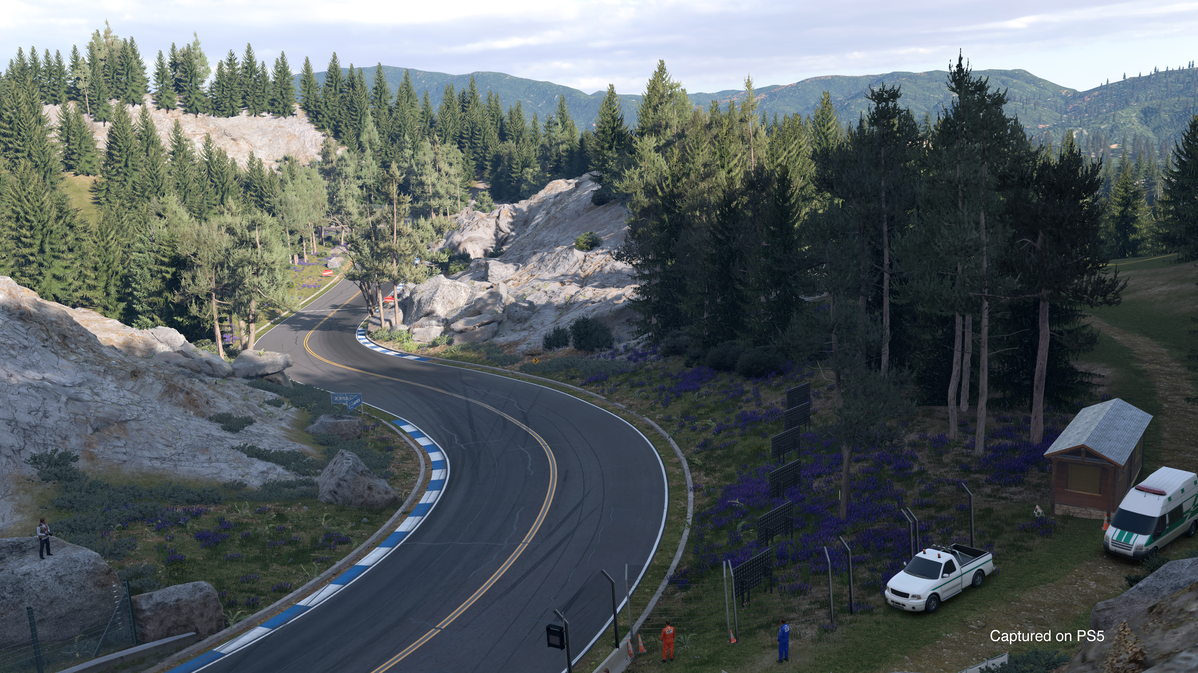 Une route sinueuse à travers un paysage de montagne, avec des arbres et un petit bâtiment.