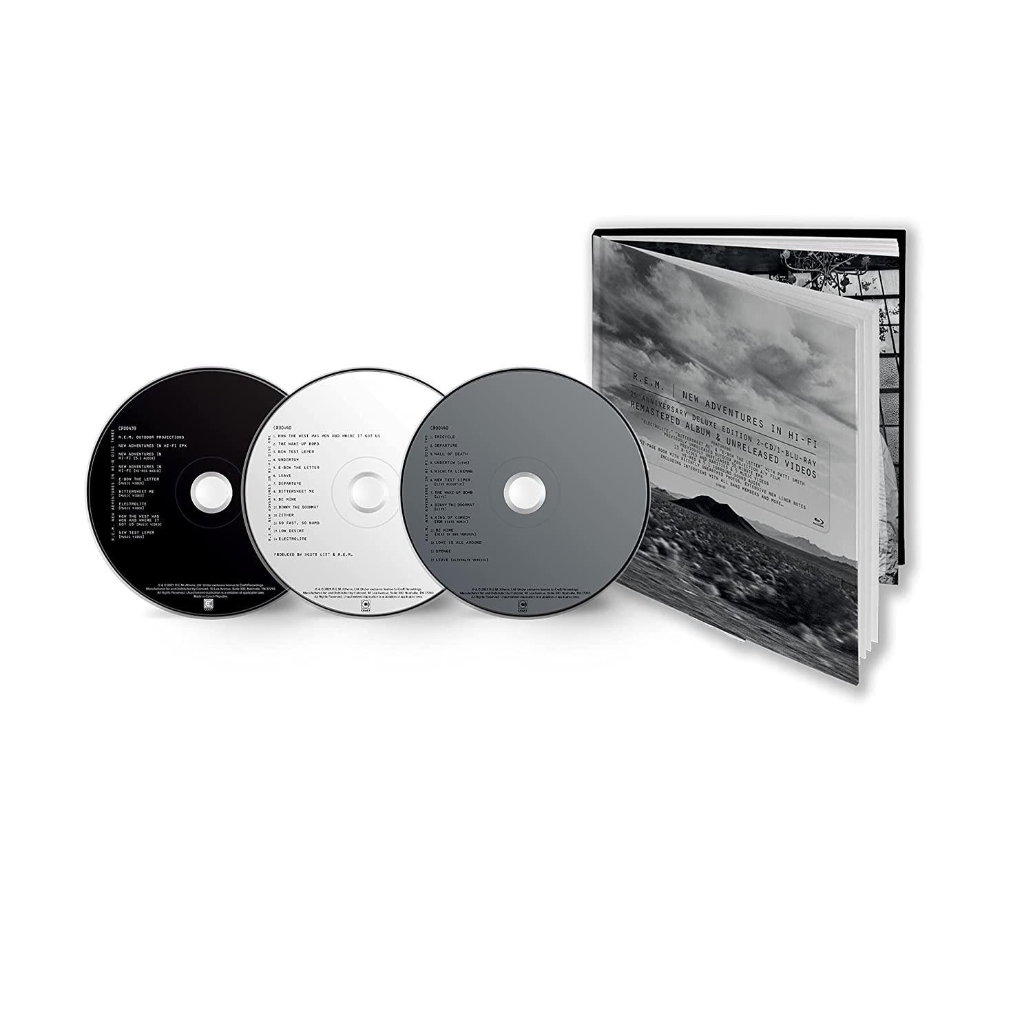 Drie cd's en een boekje met tekst en afbeeldingen, open op een wit oppervlak.