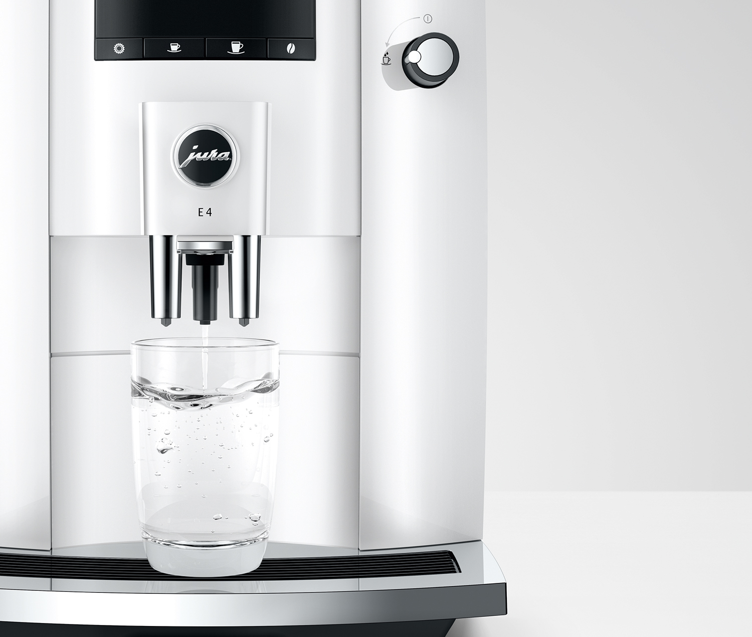 A white Jura E4 coffee machine dispensing water into a clear glass.