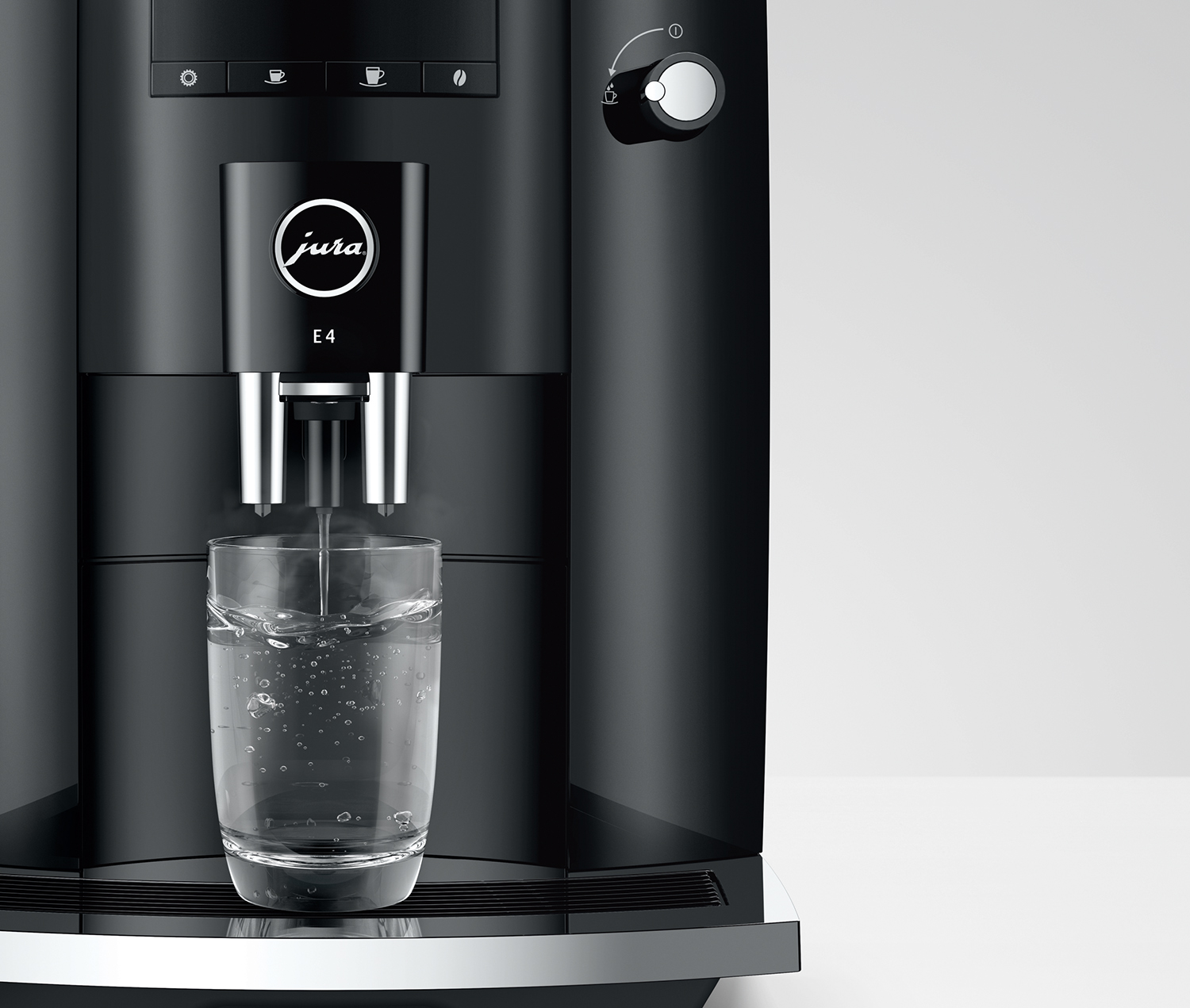 Black Jura E4 coffee machine, water filling a glass, white background.