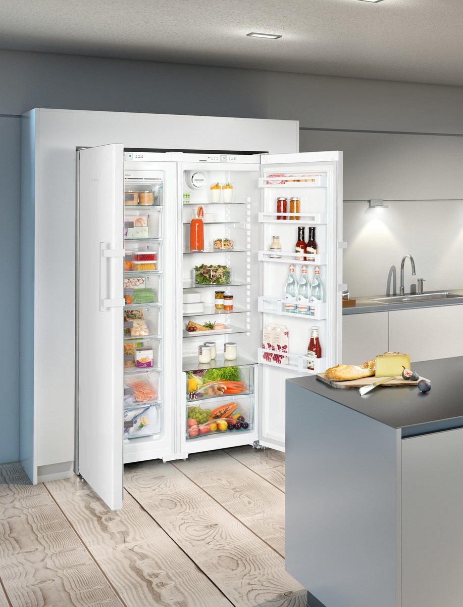 Un refrigerador lado a lado blanco, puertas abiertas mostrando el contenido. Ambiente de cocina.