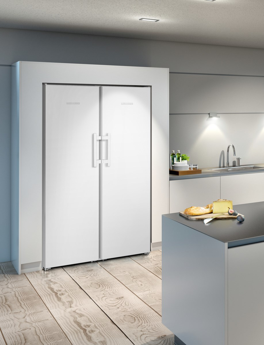 Refrigerador blanco de doble puerta con encimera de cocina y suelo de madera.