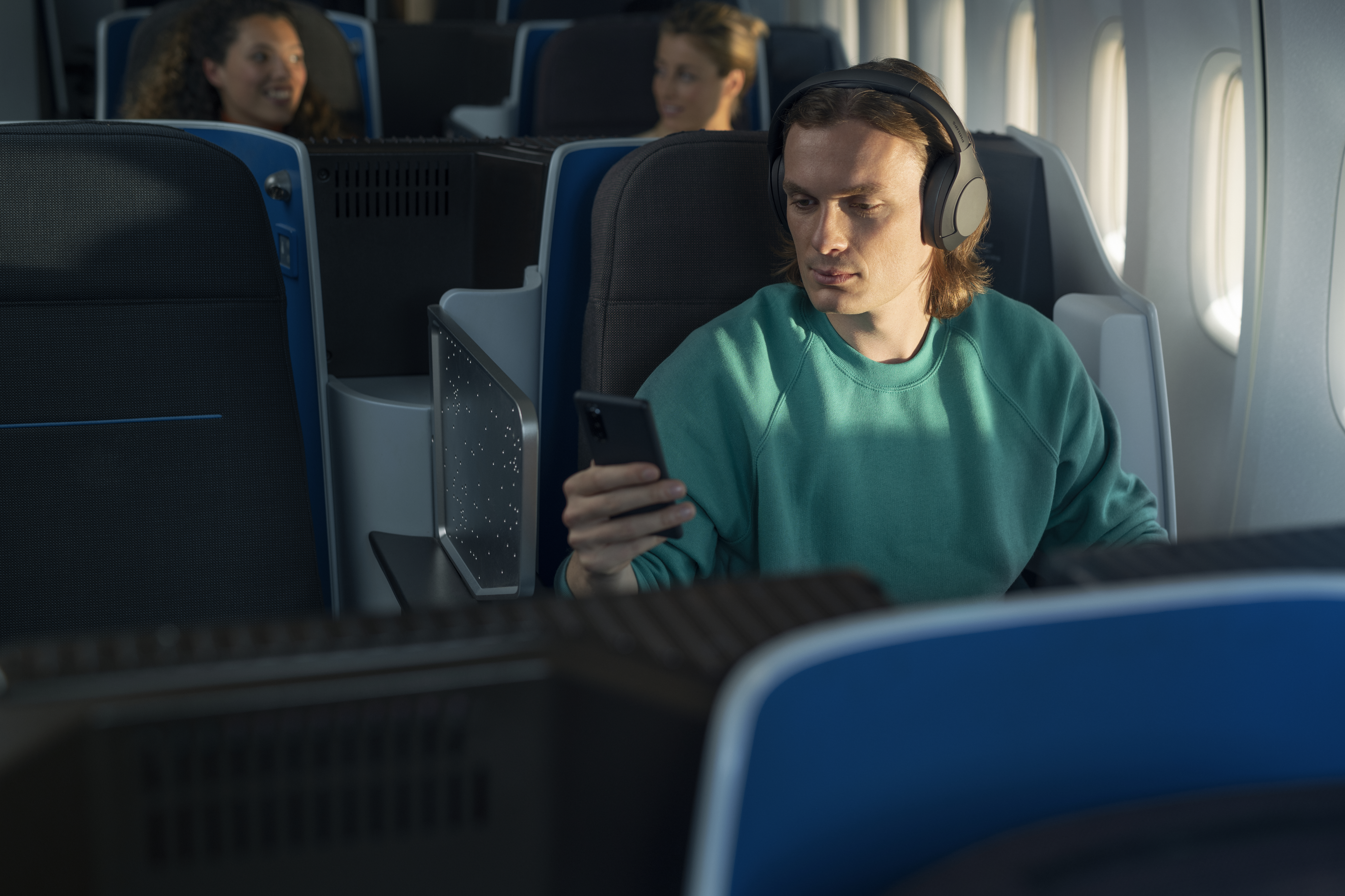 Mann im Flugzeug, der ein Telefon benutzt und Kopfhörer trägt.