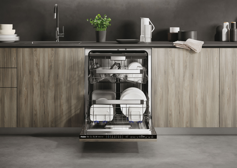 Lavavajillas abierto con platos dentro, en una cocina moderna con armarios de madera oscura.