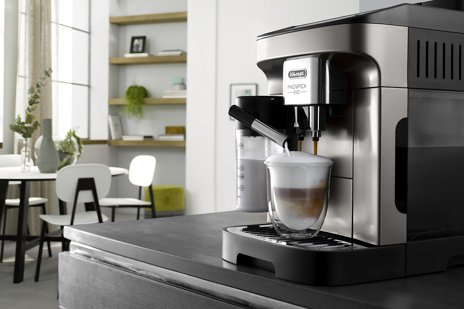 Een espressomachine die koffie in een glas maakt. Een melkcontainer staat ernaast.