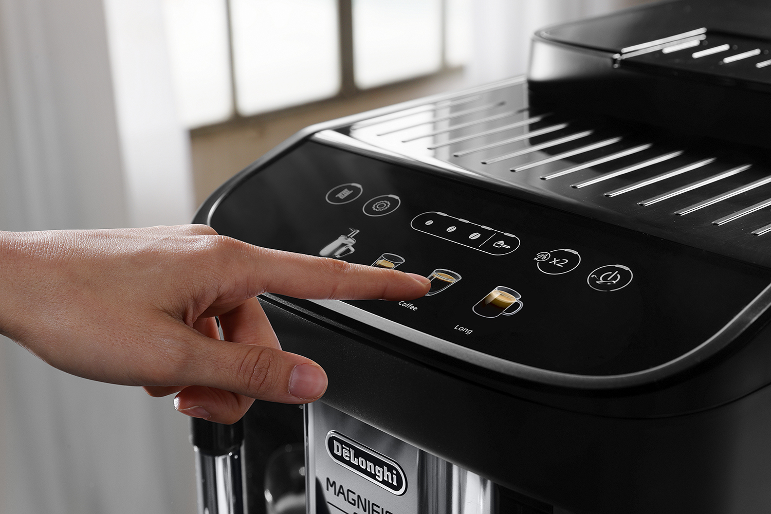 Hand drukt op een knop van een De'Longhi koffiezetapparaat. Koffie- en Long-knoppen zichtbaar.