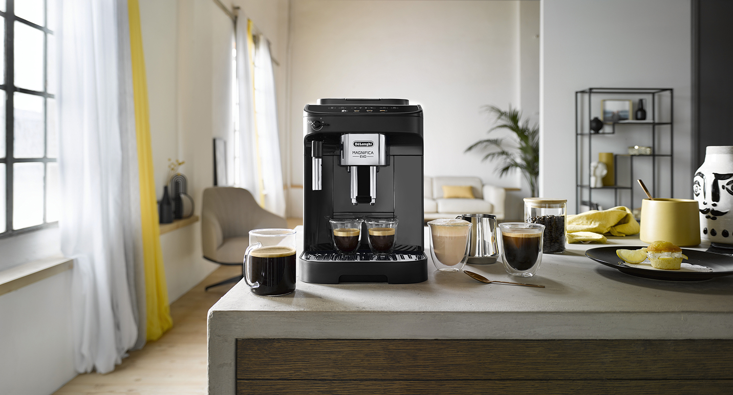 Een zwart koffiezetapparaat met twee kopjes koffie op een aanrecht.