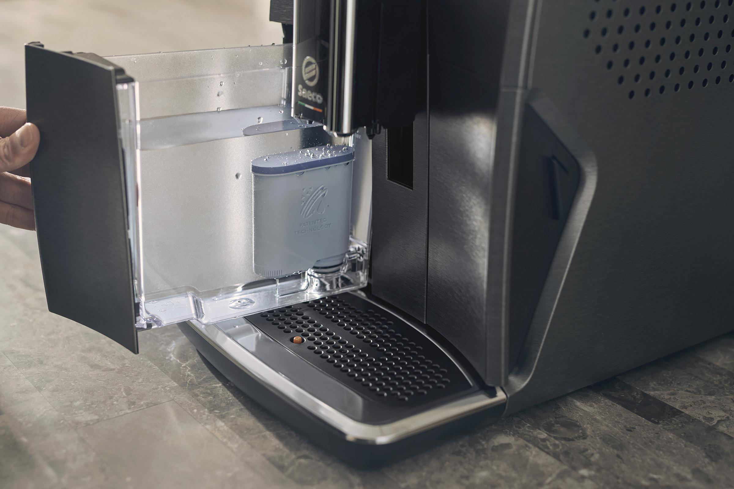 Der Wassertank einer Kaffeemaschine wird befüllt. Die Hand einer Person ist sichtbar.