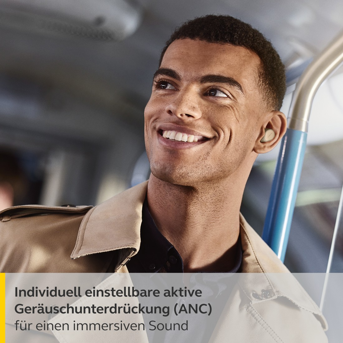 Mann mit Ohrhörern lächelt, trägt eine beige Jacke, mit Text über Ton.