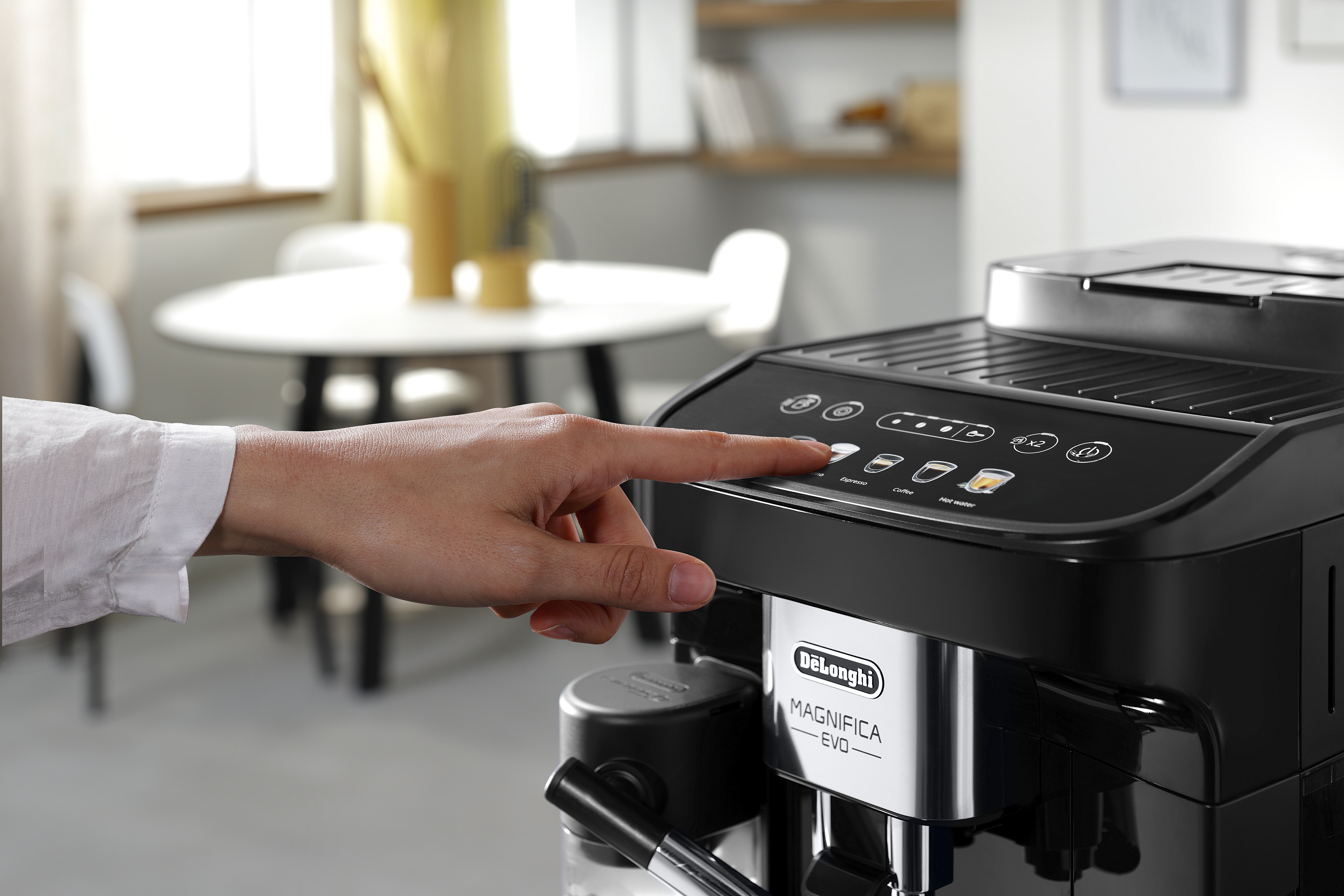 Hand van een persoon die op knoppen drukt op een zwarte koffiemachine.