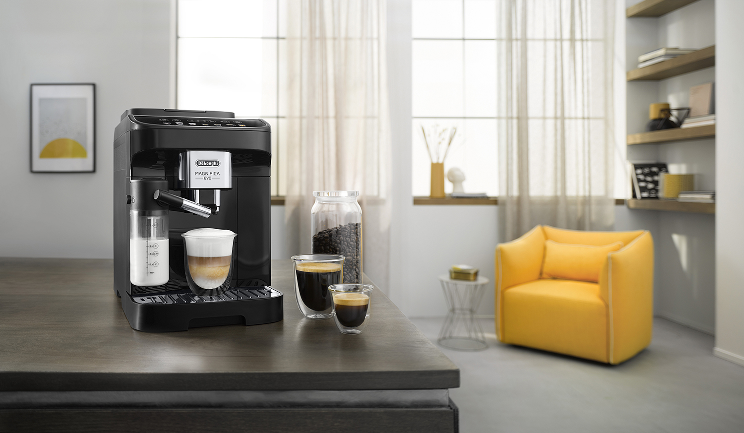 Een zwarte koffiemachine met een melkopschuimer, twee glazen koffie, koffiebonen en een gele stoel.