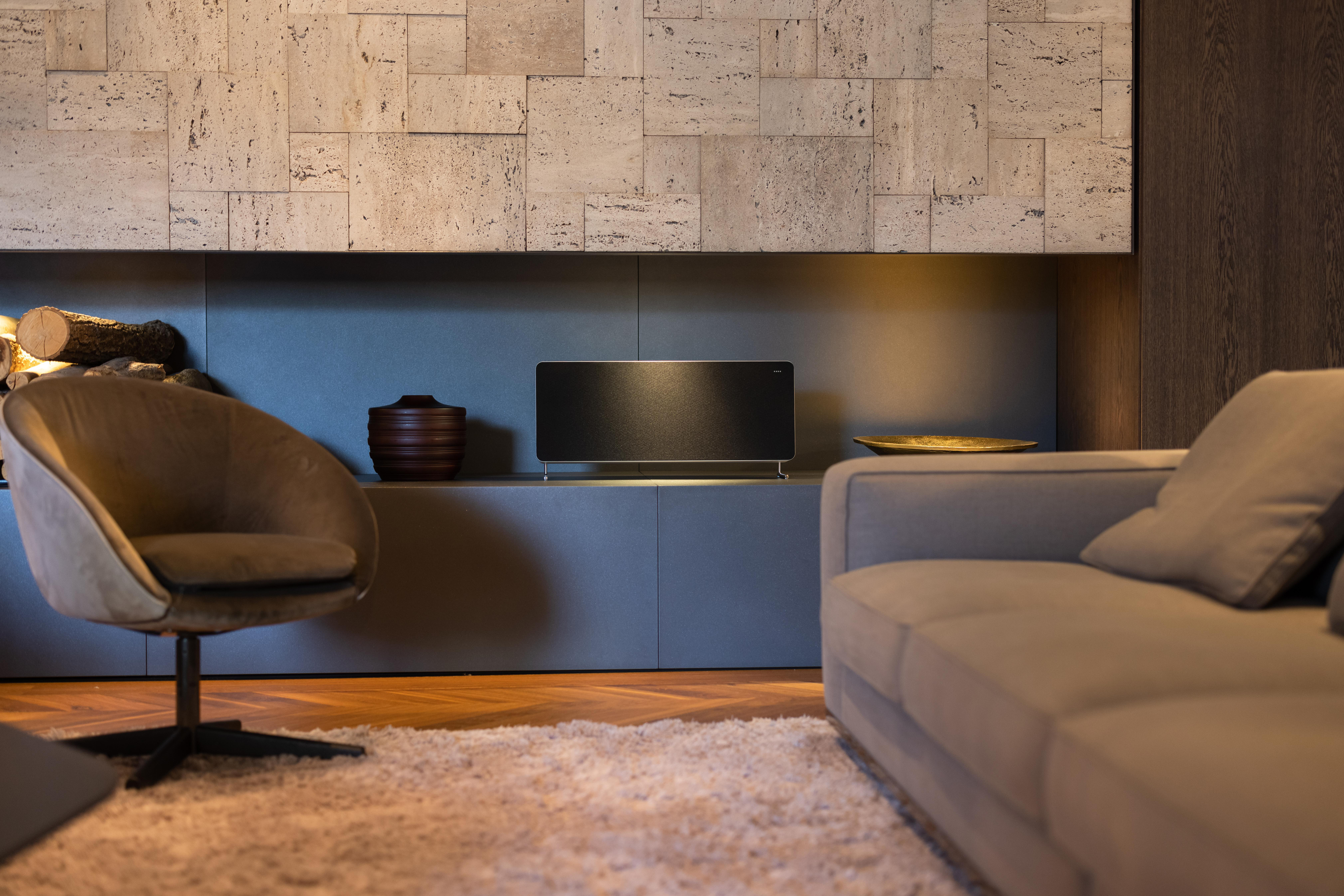 Wohnzimmer mit Soundbar, Couch und Sessel.