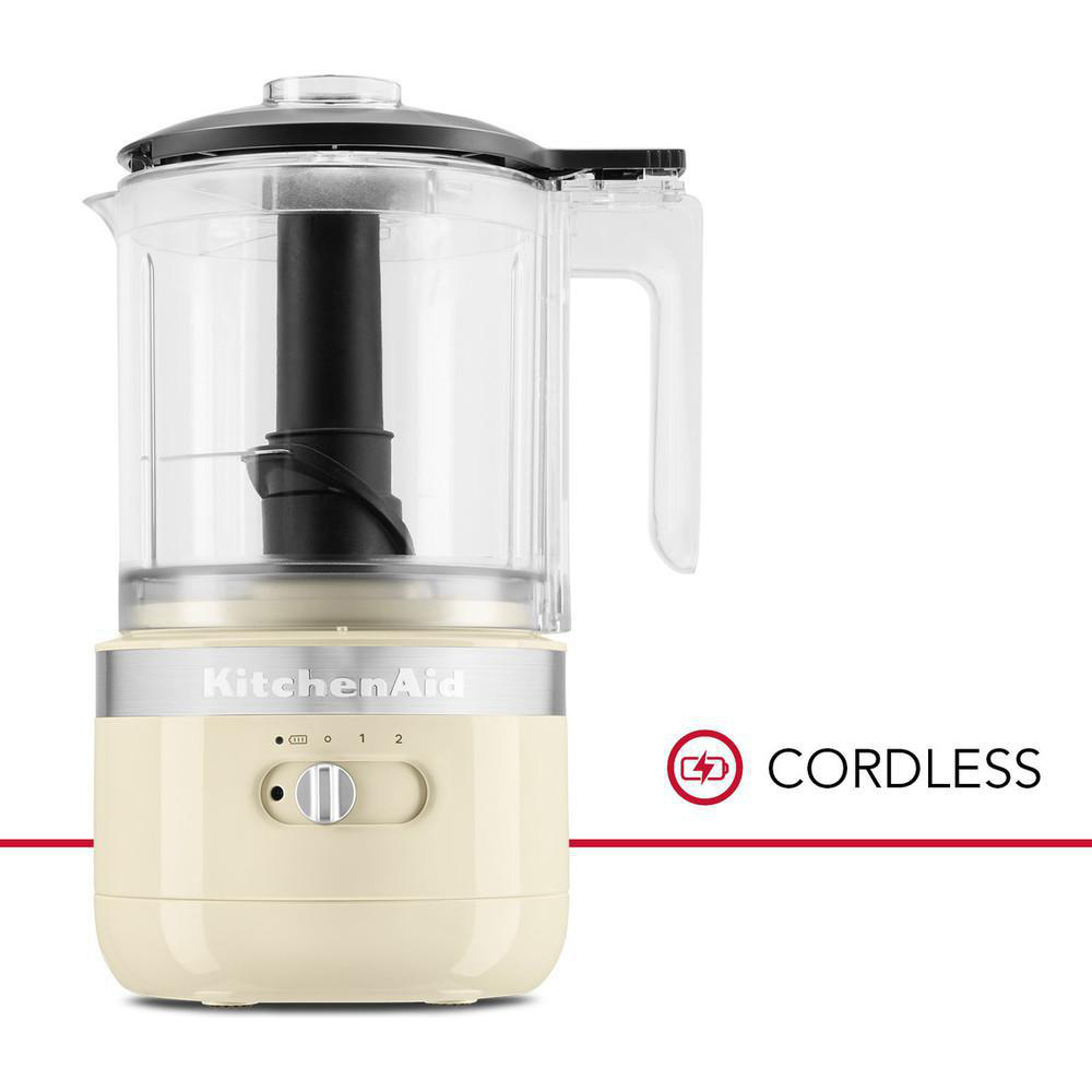 Ein cremefarbener kabelloser KitchenAid-Foodprozessor mit schwarzem Deckel und transparentem Behälter.