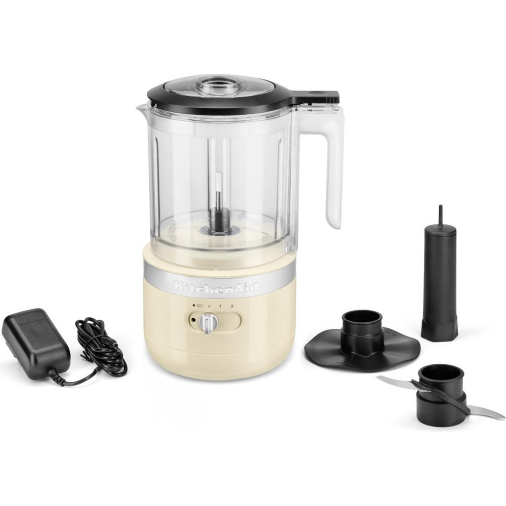 KitchenAid-Küchenmaschine mit beigefarbenem Sockel, transparentem Behälter und mehreren Aufsätzen.
