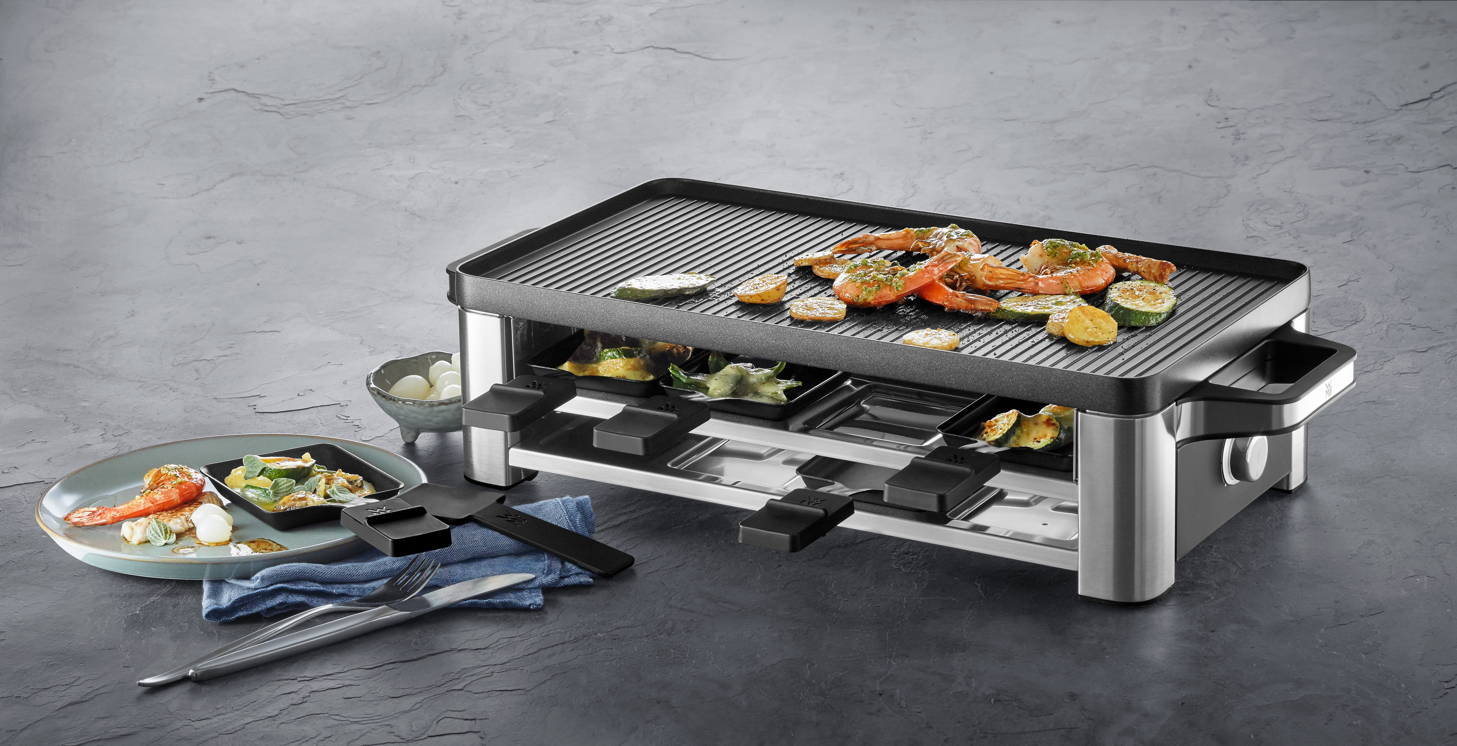 Raclette-Grill mit Garnelen, Zucchini und Käse. Ein Teller mit Essen.
