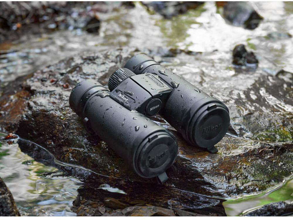 Binocolo nero su roccia bagnata con acqua.