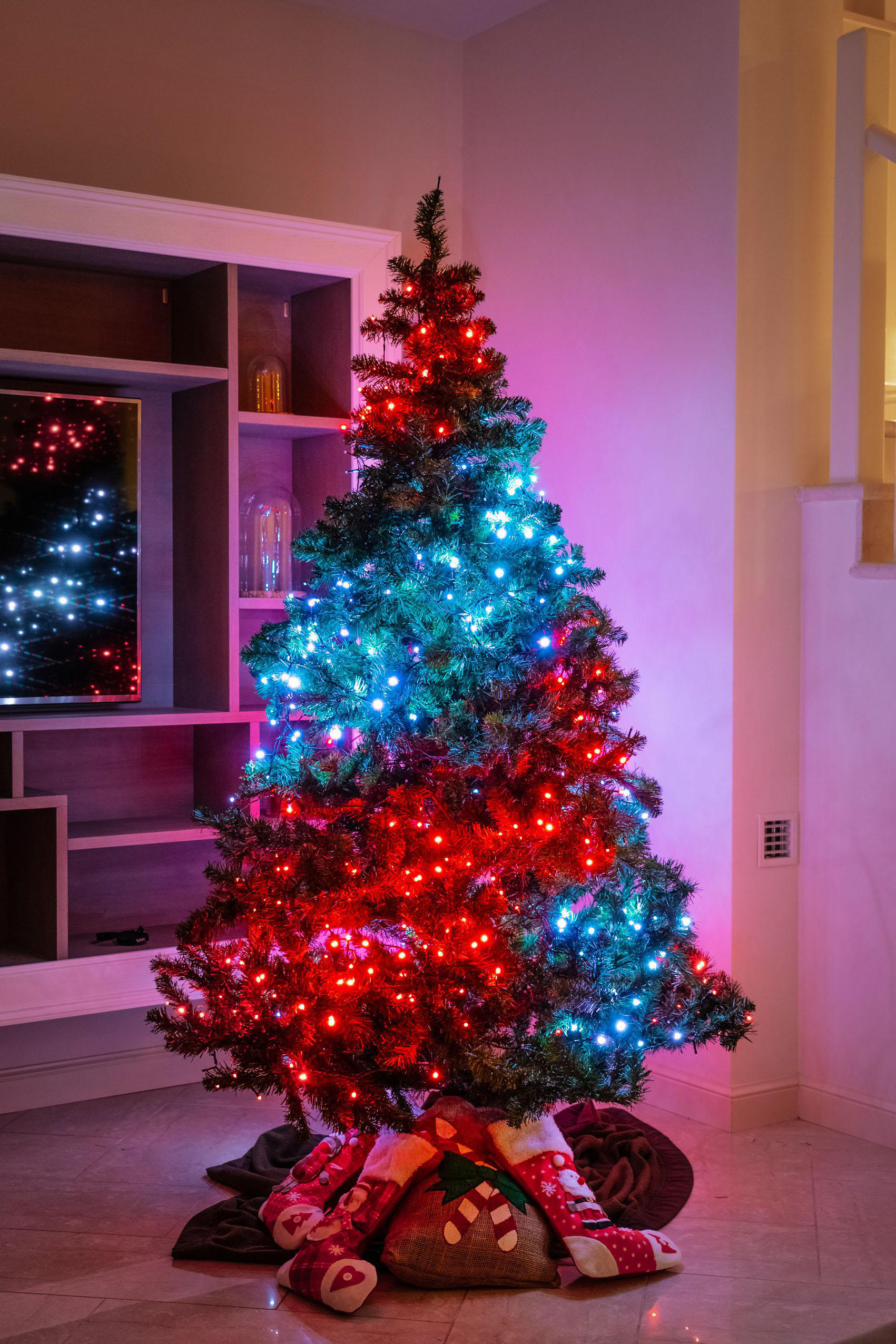 Ein Weihnachtsbaum mit roten und blauen Lichtern mit Strümpfen und einem Sockel.