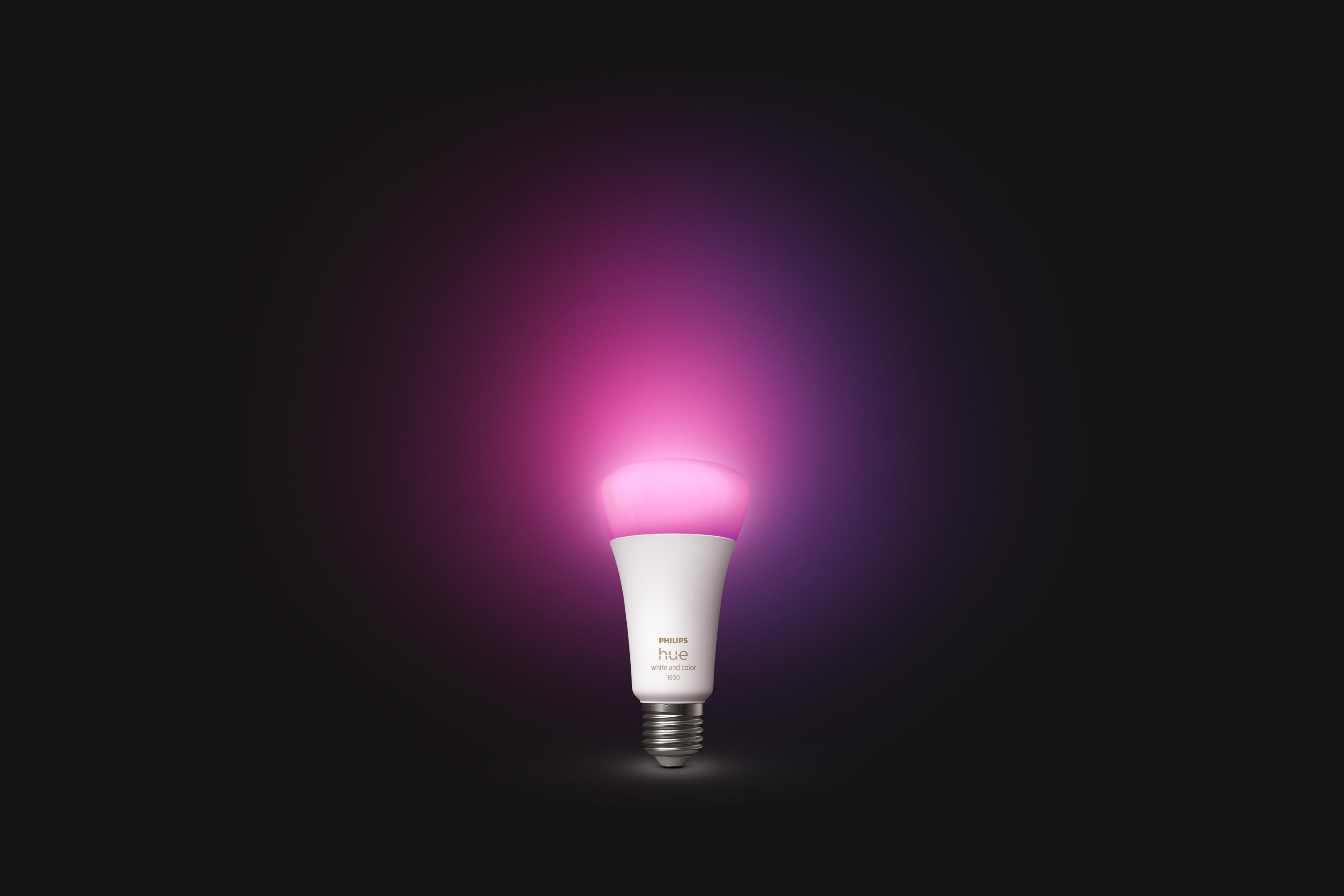 Eine Philips Hue Glühbirne, die mit rosa und lila Licht leuchtet. Der Hintergrund ist dunkel.