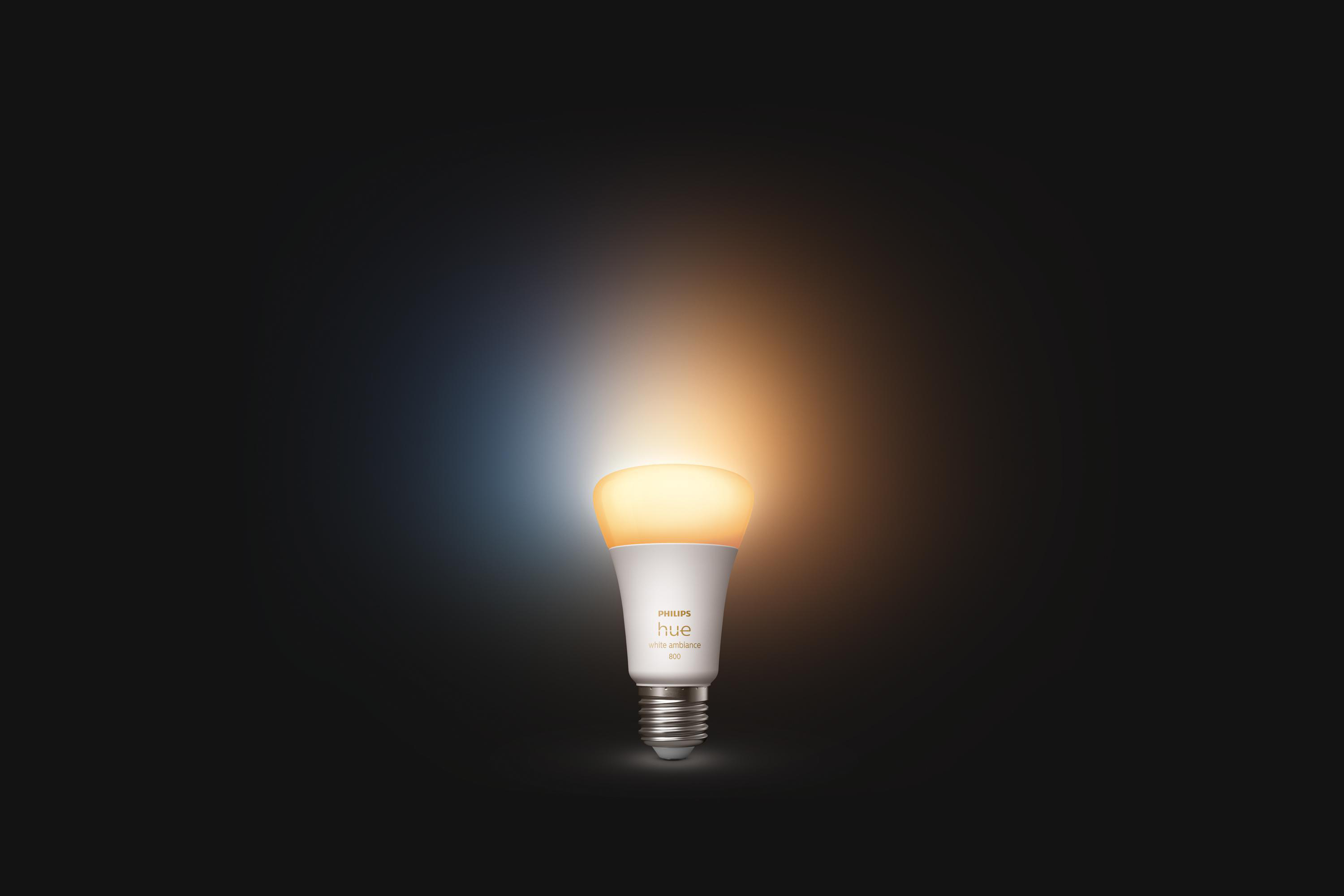 Philips Hue Glühbirne leuchtet gelb vor dunklem Hintergrund.