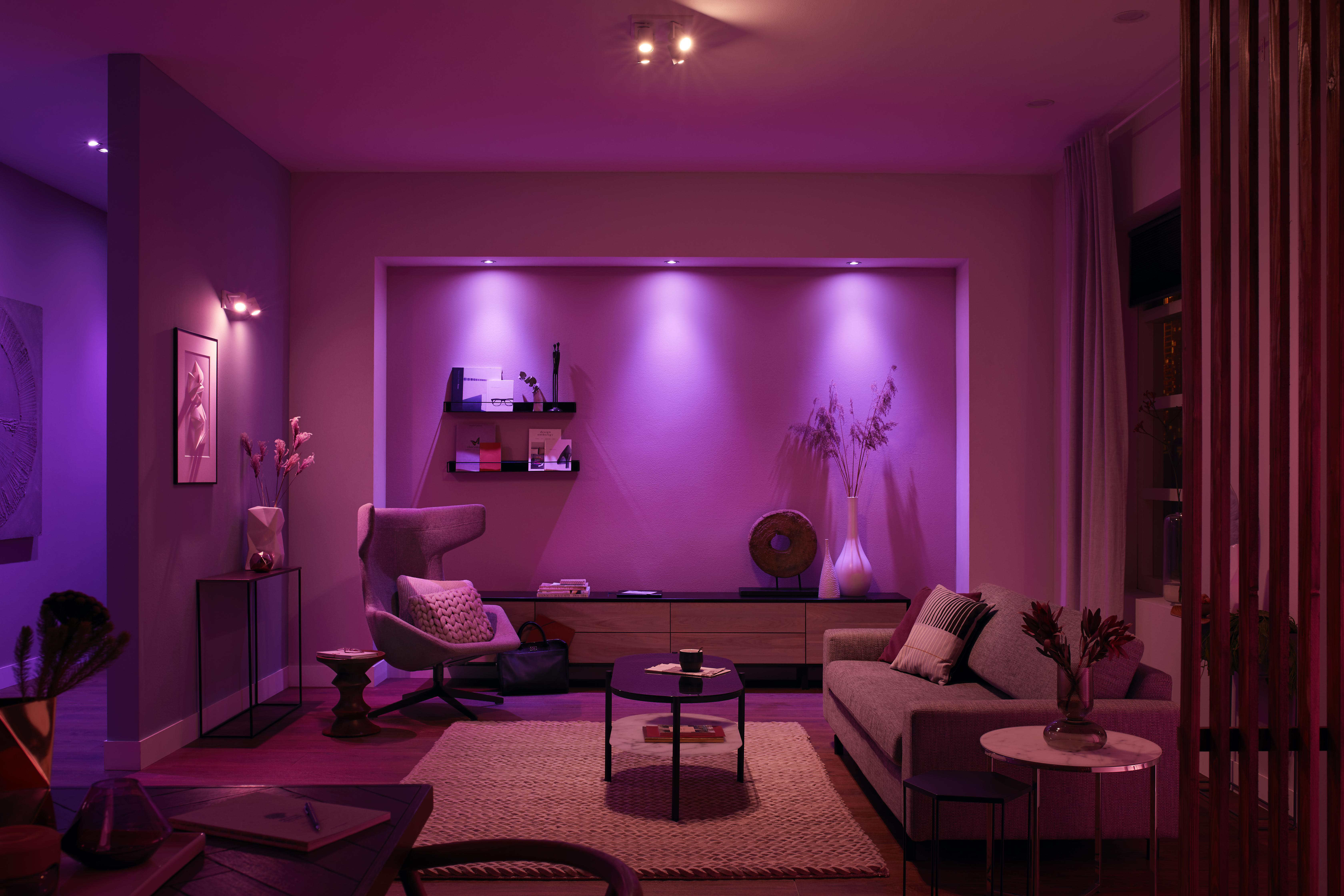 Wohnzimmer mit lila Beleuchtung, Sofa, Kunstwerken und Regalen. Modernes Interieur.