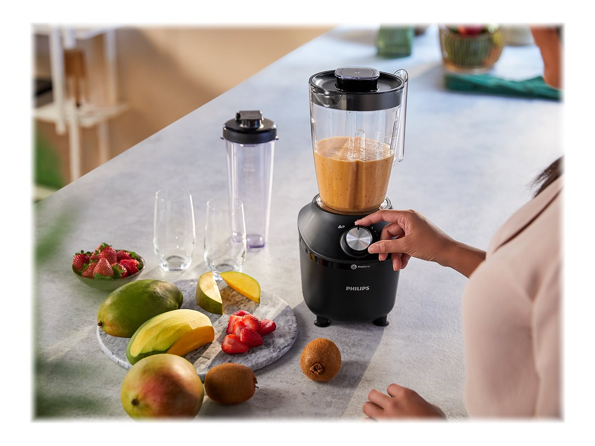 Person benutzt Mixer mit Früchten in der Nähe auf einer Küchentheke.