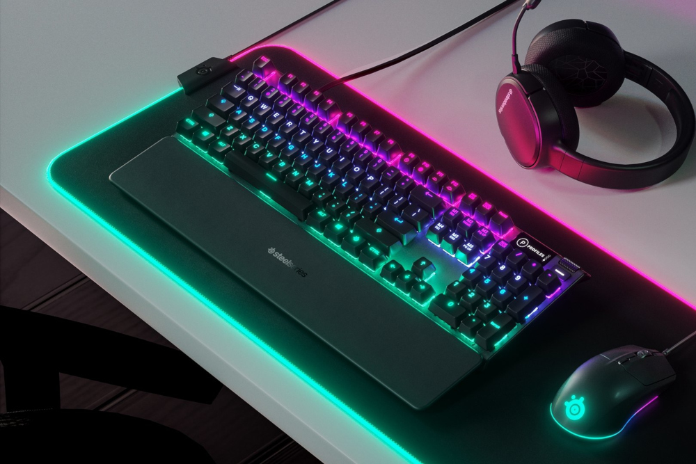 A gaming setup with a keyboard, mouse, headset, and a mat with RGB lighting.