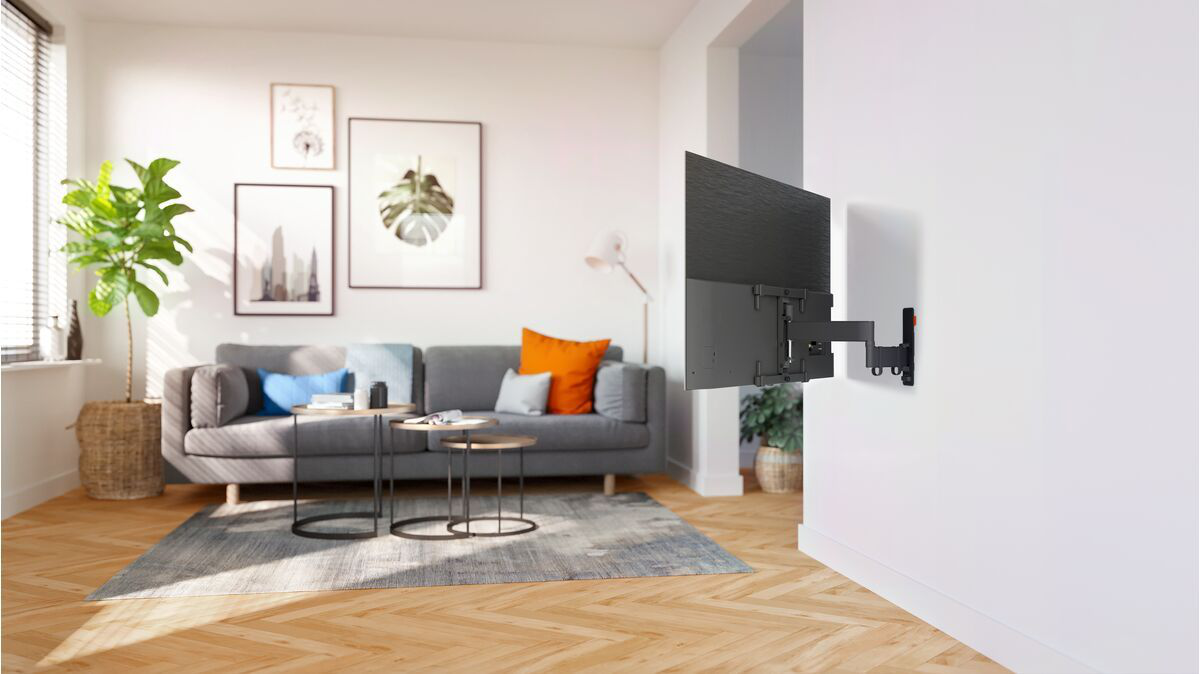 Wohnzimmer mit TV an Wandhalterung, Sofa und Couchtischen.