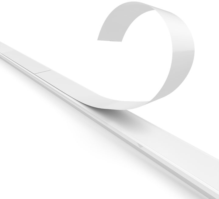 White adhesive strip being peeled away from a white surface. The strip is curved.