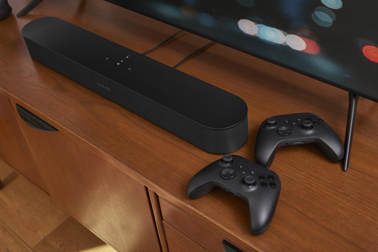 Schwarze Soundbar, zwei schwarze Controller und ein Fernseher auf Holzoberfläche.