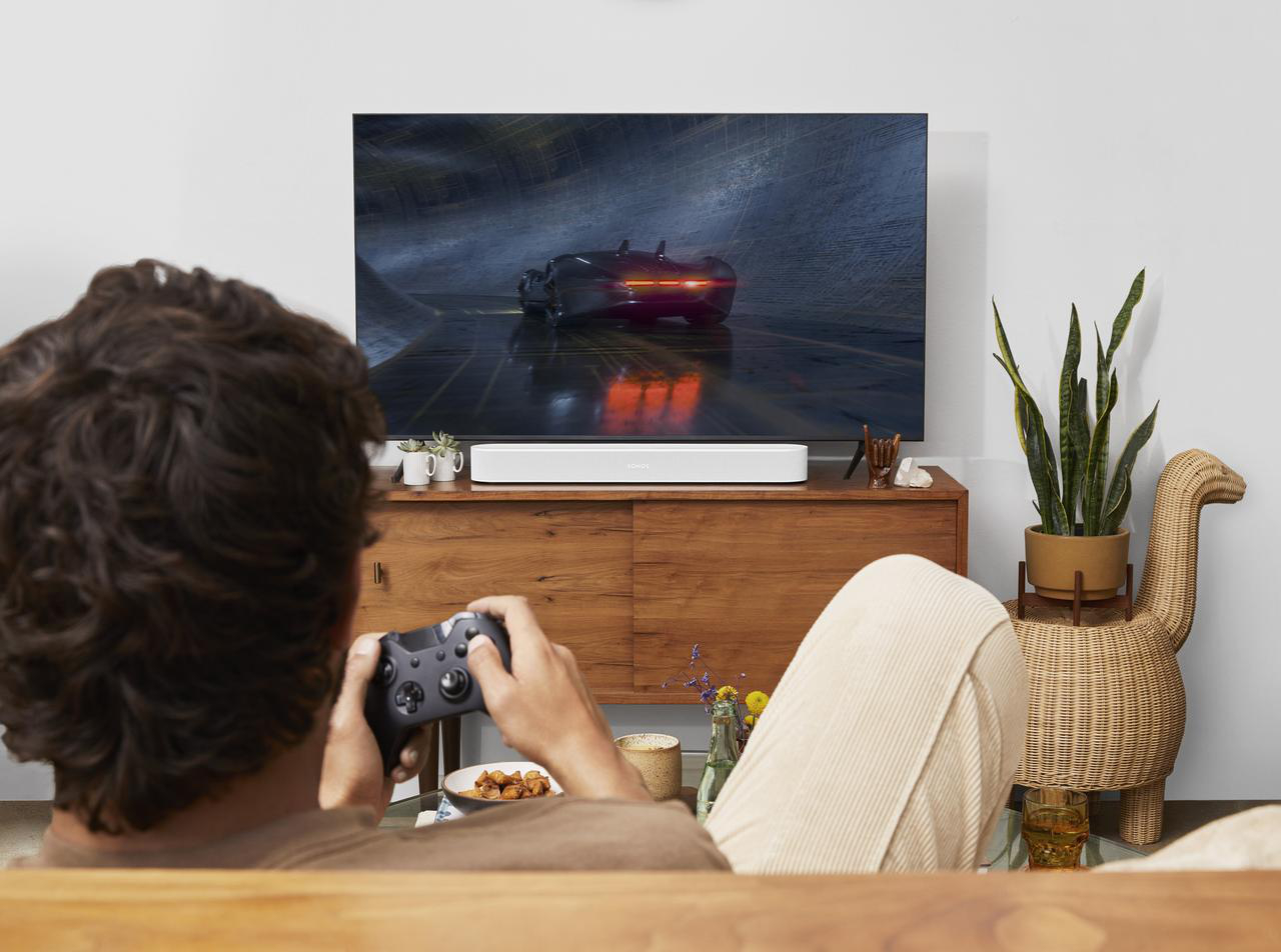 Mann spielt Videospiele auf einem Fernseher. Unter dem Bildschirm befindet sich eine weiße Soundbar.