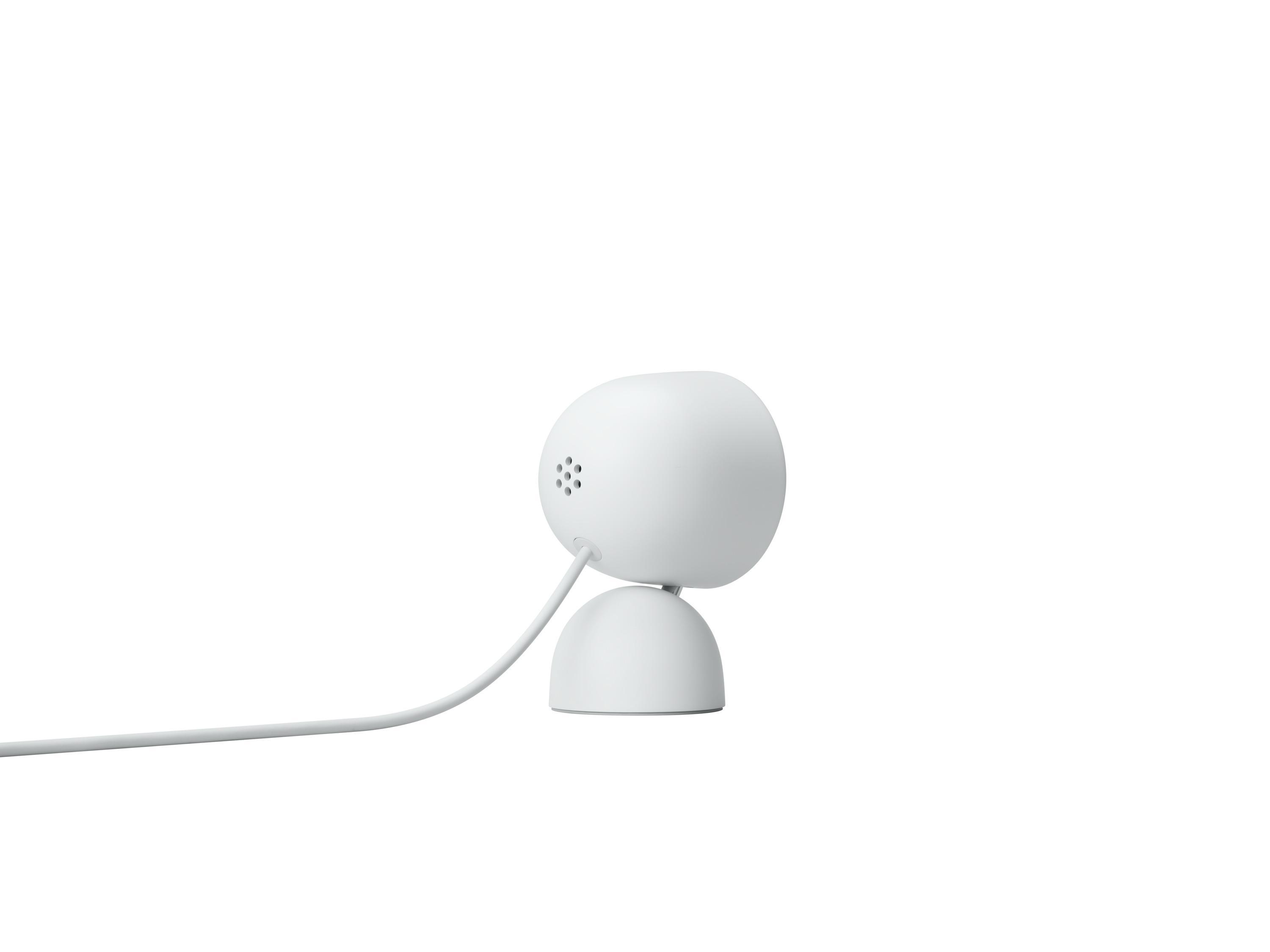 Eine weiße Google Nest Cam auf weißer Basis, mit einem Kabel, das sich nach links erstreckt.